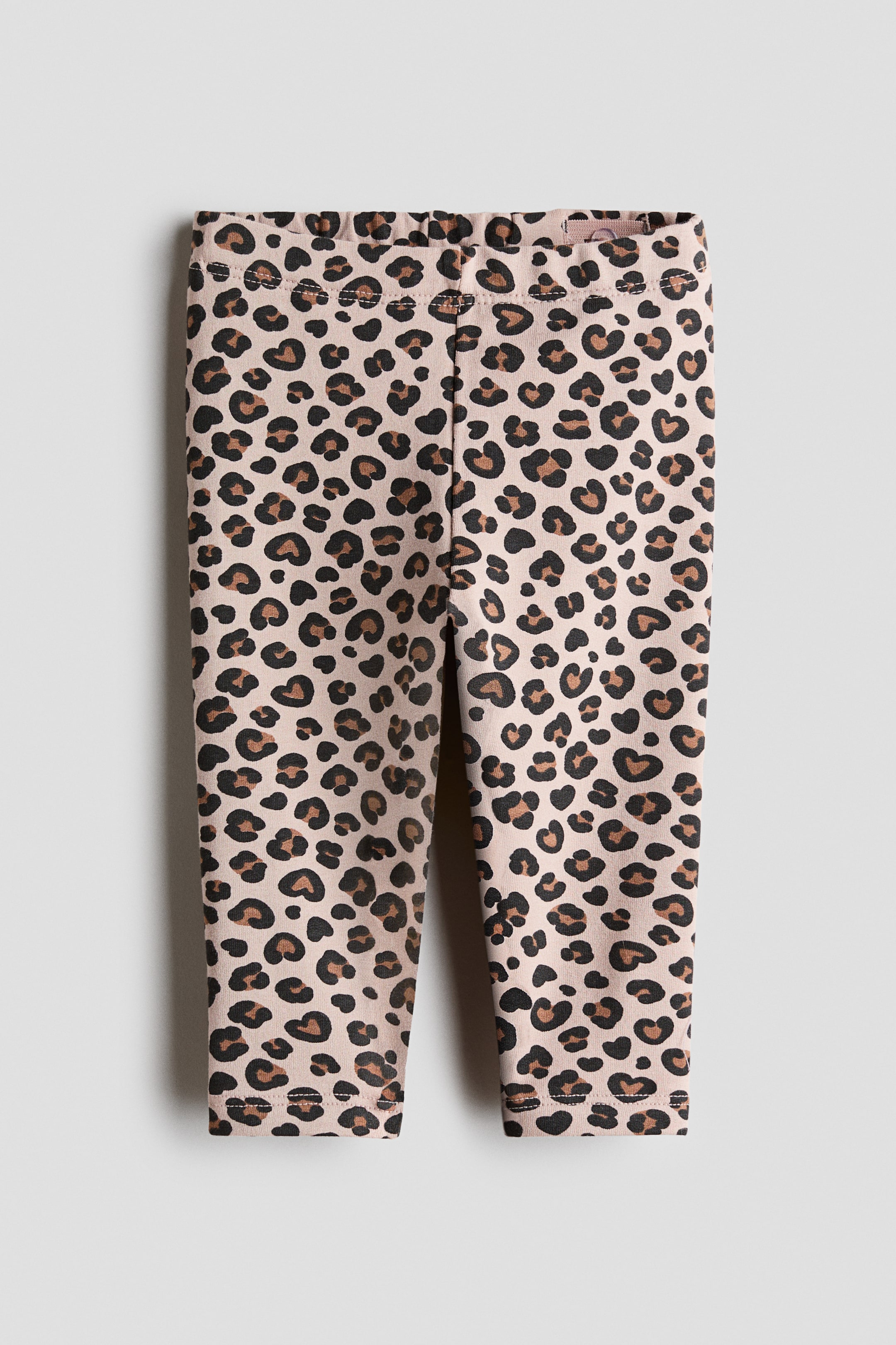 View larger image: Leggings are displayed from the front, showcasing a leopard print pattern with black and brown spots on a light beige cotton jersey. They are crafted with an adjustable, elasticated waistband.