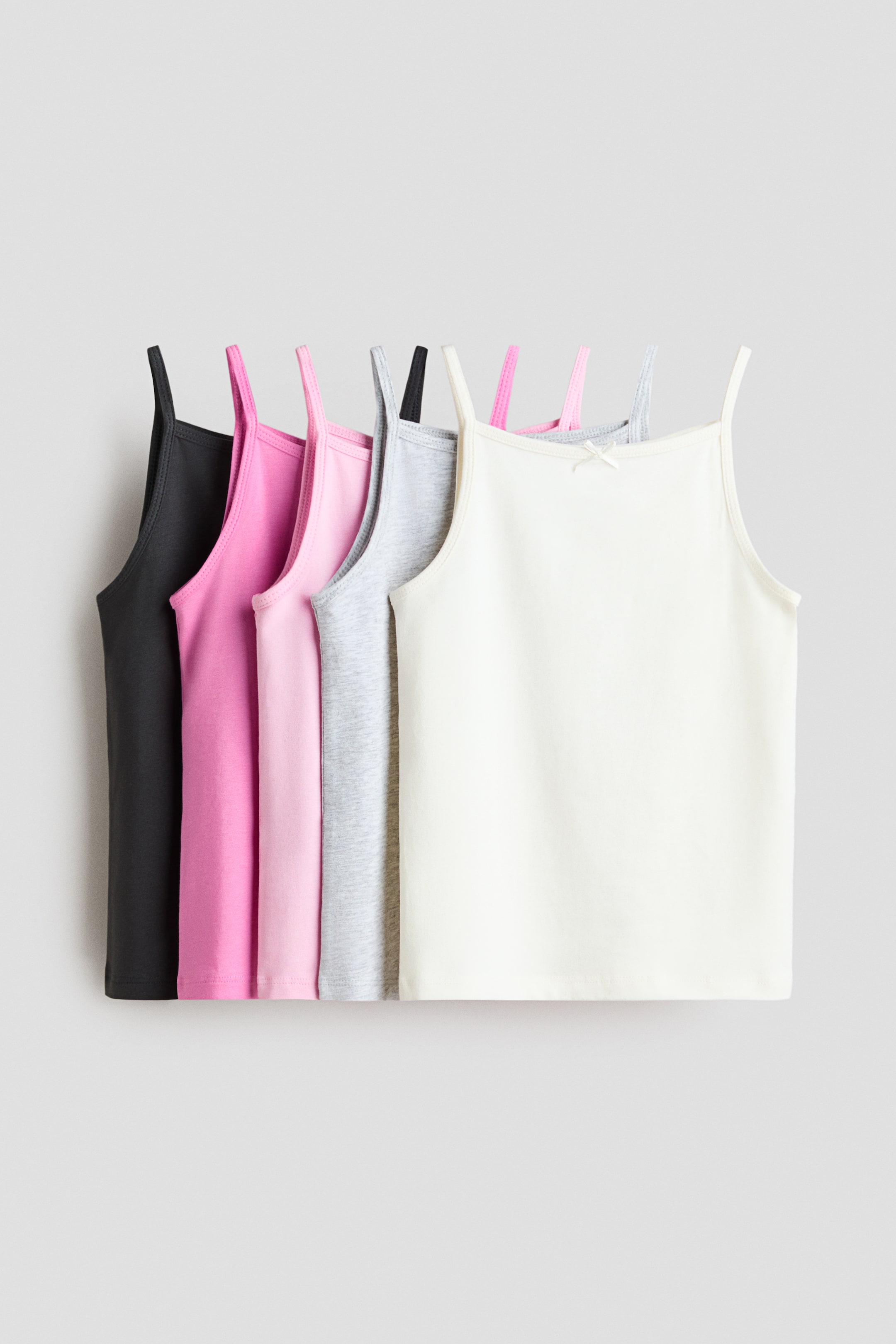 View larger image: A set of five cotton jersey tank tops in black, bright pink, light pink, gray marl, and off-white is displayed in a front view. Each tank features narrow shoulder straps and picot trims at the neckline, with a decorative satin bow visible on the front of the off-white top.
