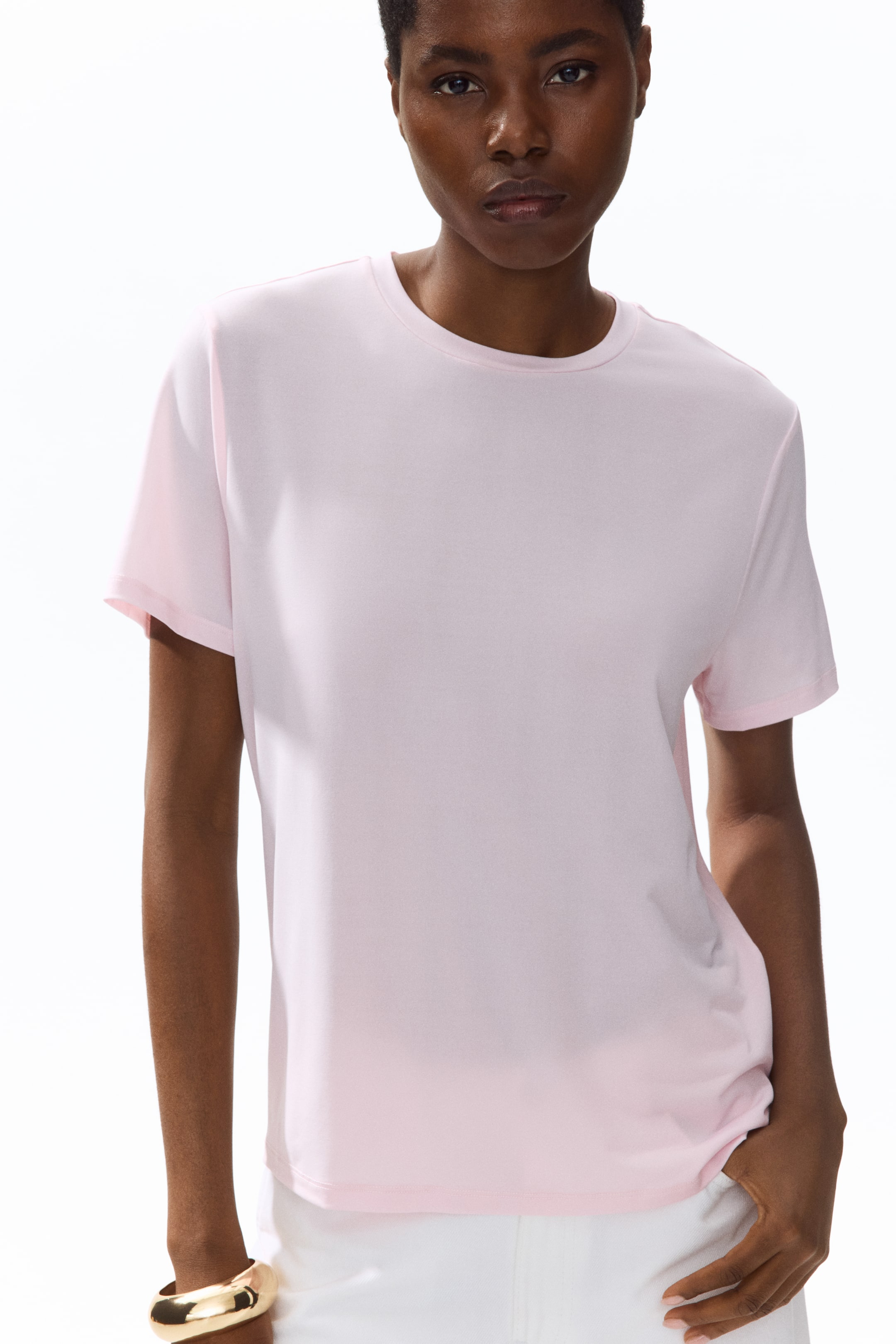 View larger image: A light pink t-shirt featuring a round neckline and short sleeves, showcasing smooth fabric and a relaxed silhouette while facing forward.