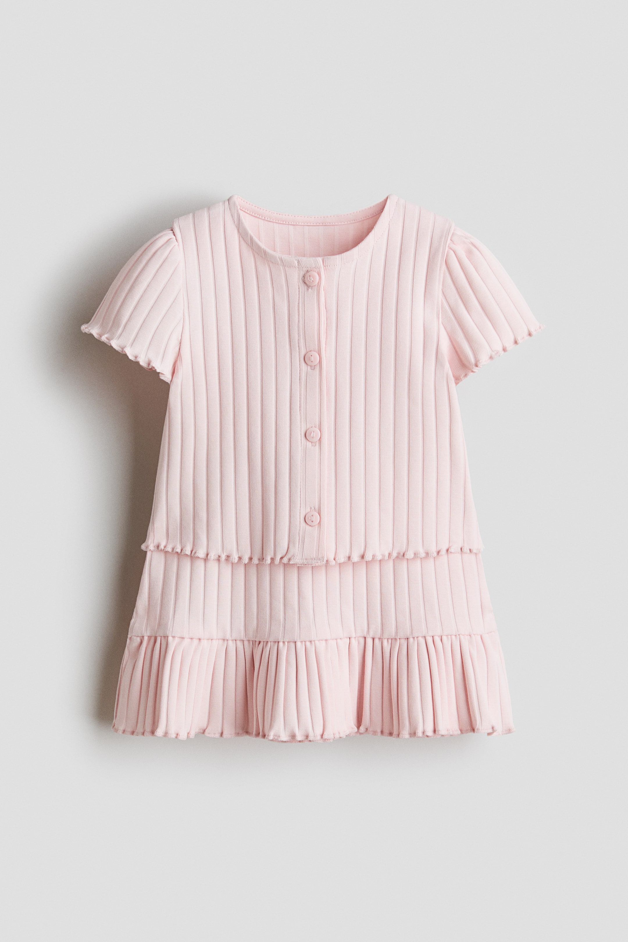 View larger image: This pink ribbed dress showcases a round neckline, wavy-edged short sleeves, and a button placket running down the front with matching pink buttons. The skirt features multiple ribbed tiers, with the bottom tier appearing pleated.