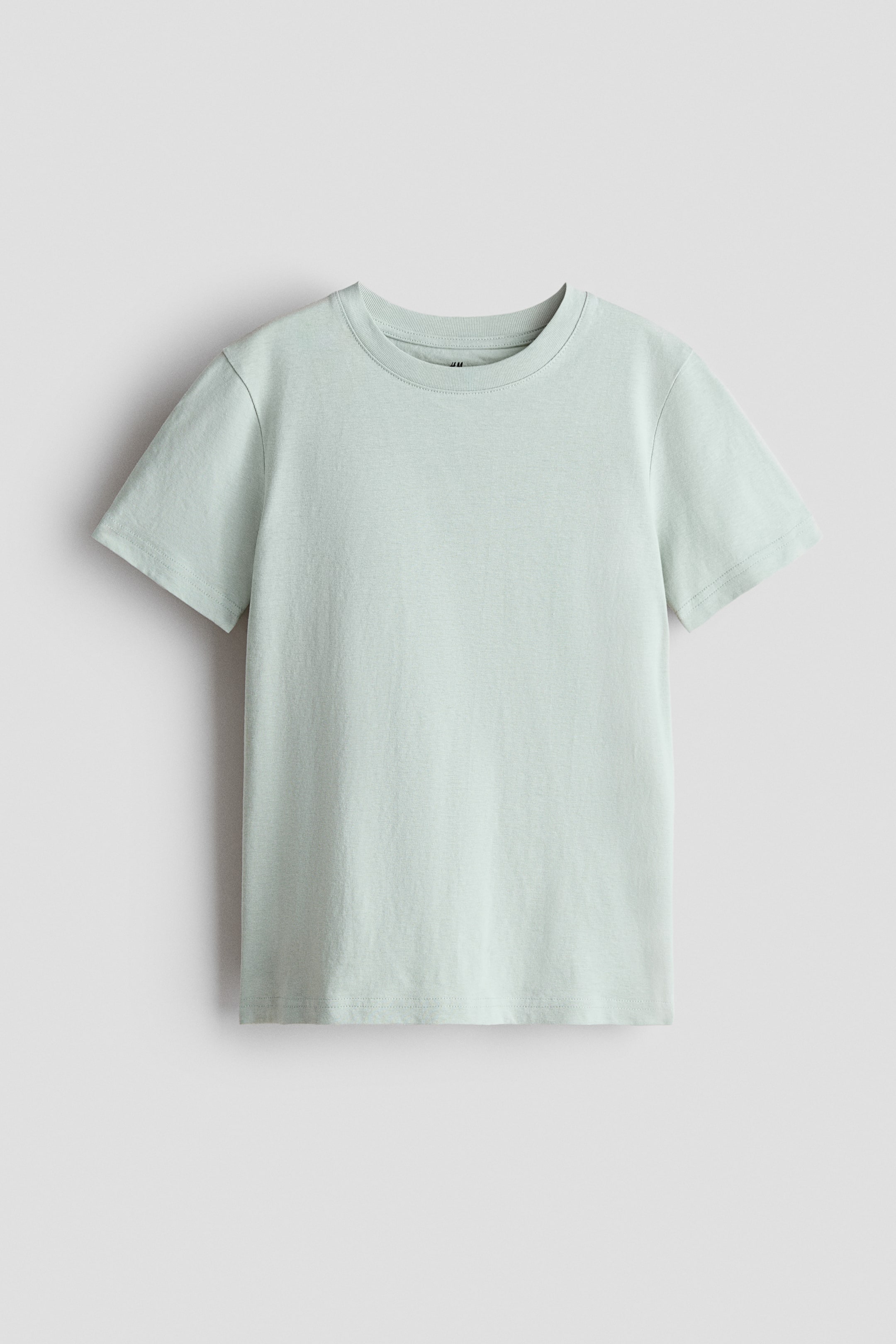 Agrandir l'image: T-shirt en jersey de coton. Le T-shirt présente son DEVANT, arborant une couleur vert pâle, un col rond côtelé, des manches courtes et un ourlet droit.