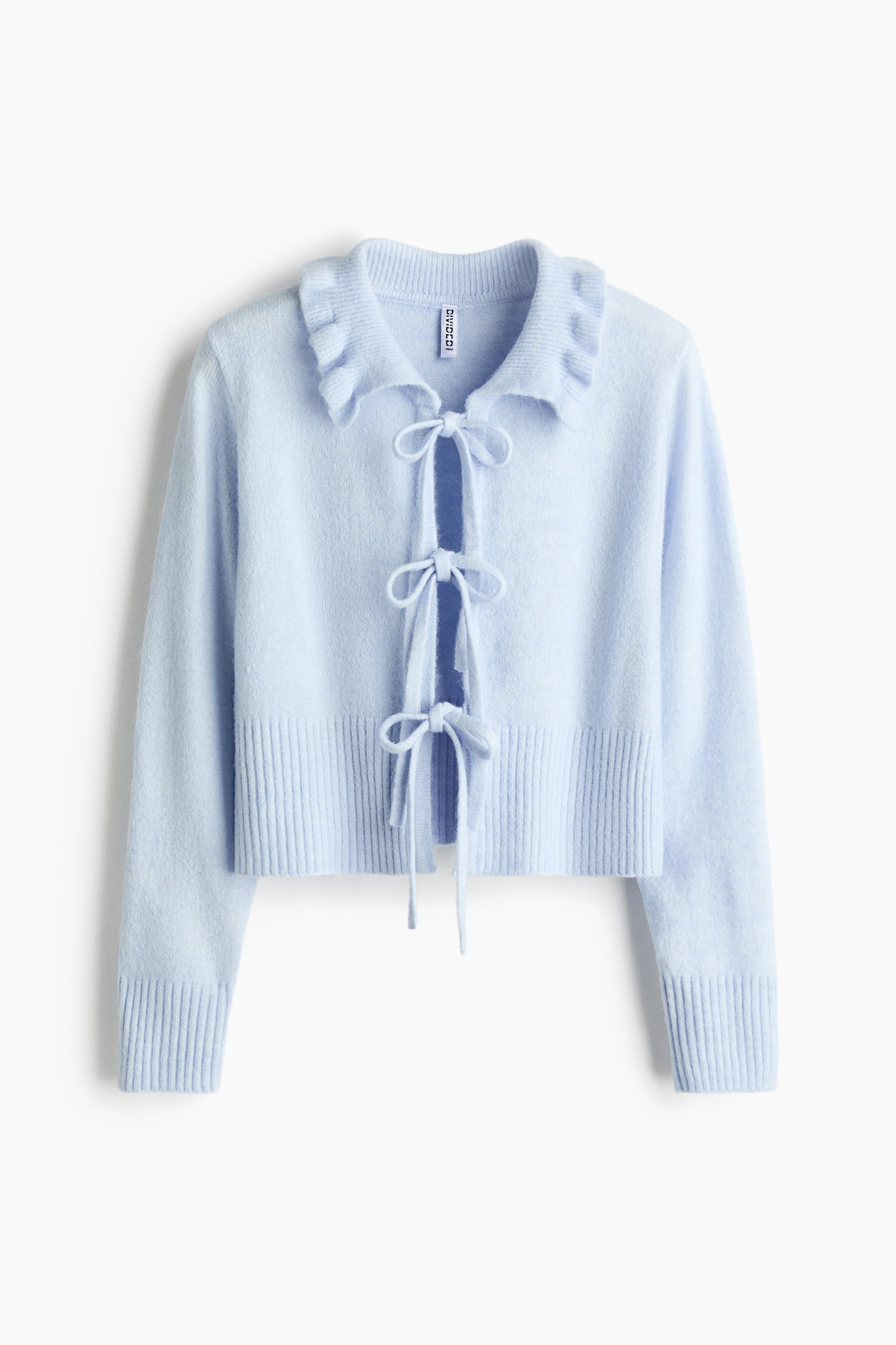 이미지 확대 보기: 부드러운 니트의 앞면 카디건은 둥근 목선과 프릴 장식의 옷깃, 전면에 세 쌍의 끈 묶음이 특징입니다. 소매와 밑단에는 골지무늬가 있습니다.