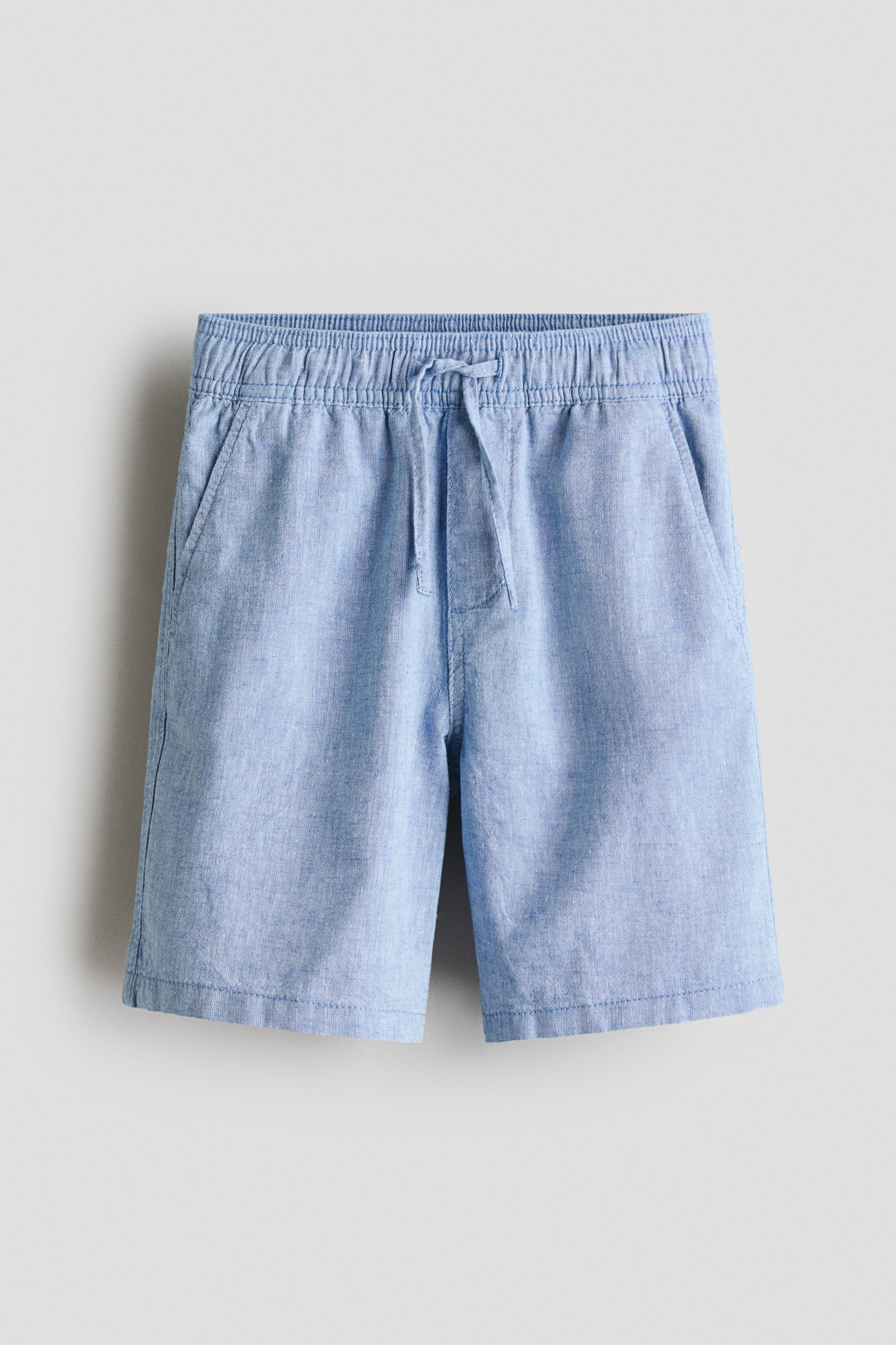 Ver imagen más grande: Pantalones cortos azul claro en tejido de algodón y lino, presentados de frente, con cintura elástica con cordón ajustable, bragueta falsa y bolsillos frontales diagonales.
