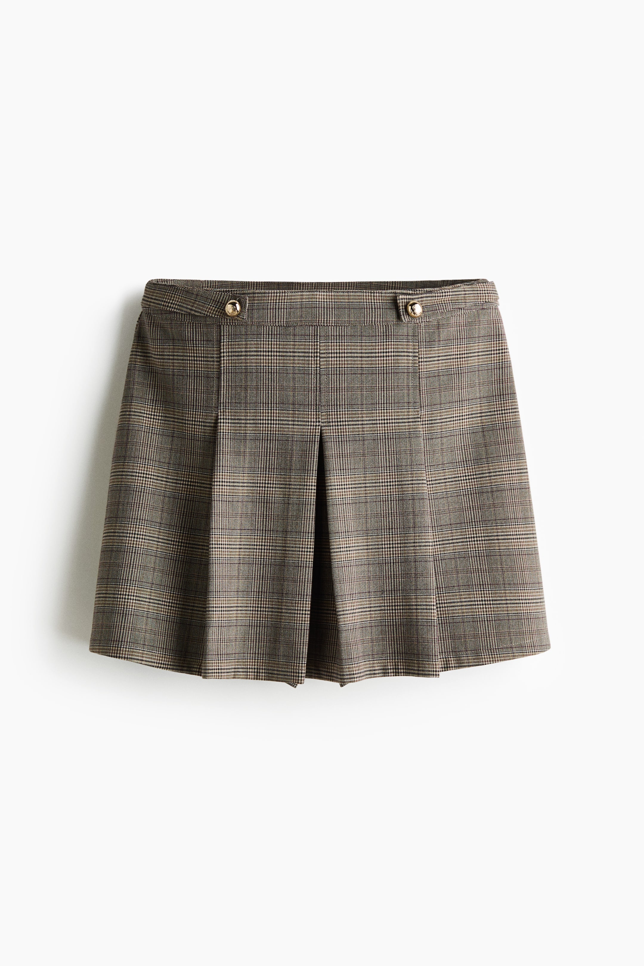 View larger image: A front view of a brown and beige plaid mini skirt shows a structured waistband with two decorative side tabs adorned with round, gold-tone buttons. The skirt features deep box pleats along the front, creating a structured, flared silhouette.