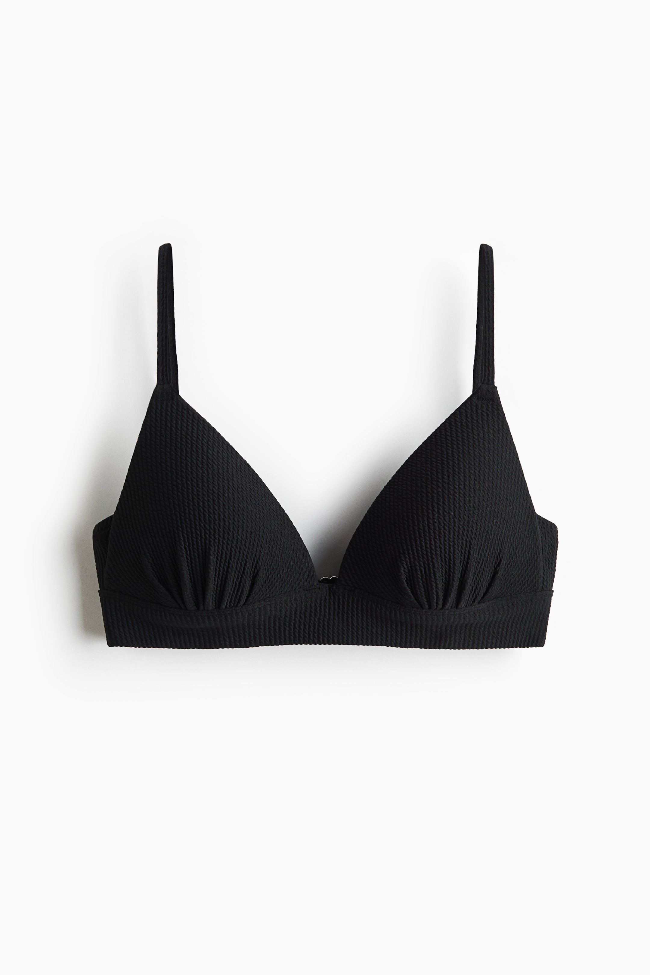 Visualizza immagine più grande: Un top bikini nero si presenta frontalmente, caratterizzato da un tessuto strutturato e coppe triangolari modellate. Le coppe mostrano una leggera arricciatura alla base e si collegano con un piccolo anello metallico, mentre sottili spalline si estendono verso l'alto.