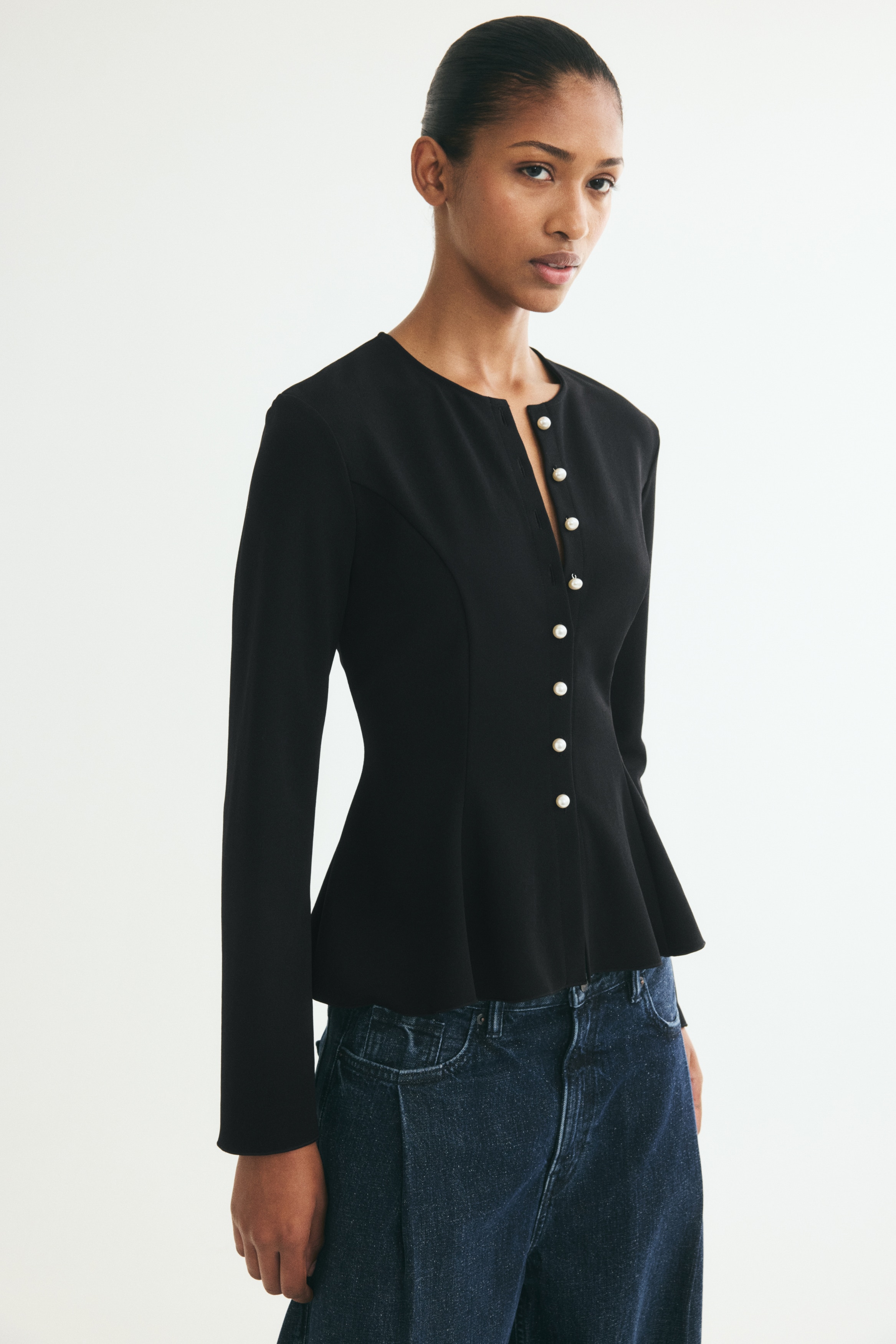 Má»t chiếc áo khoác peplum mà u Äen ÄÆ°á»£c chụp chÃnh diá»n, ná»i báºt vá»i cá» tròn không ve và phần Äóng phÃa trưá»c bằng tám nút ngá»c trai trắng. Trang phục có các ÄÆ°á»ng may dá»c tạo phom, xòe nhẹ ra thà nh gấu peplum và tay dà i hÆ¡i loe á» phần cá» tay.
