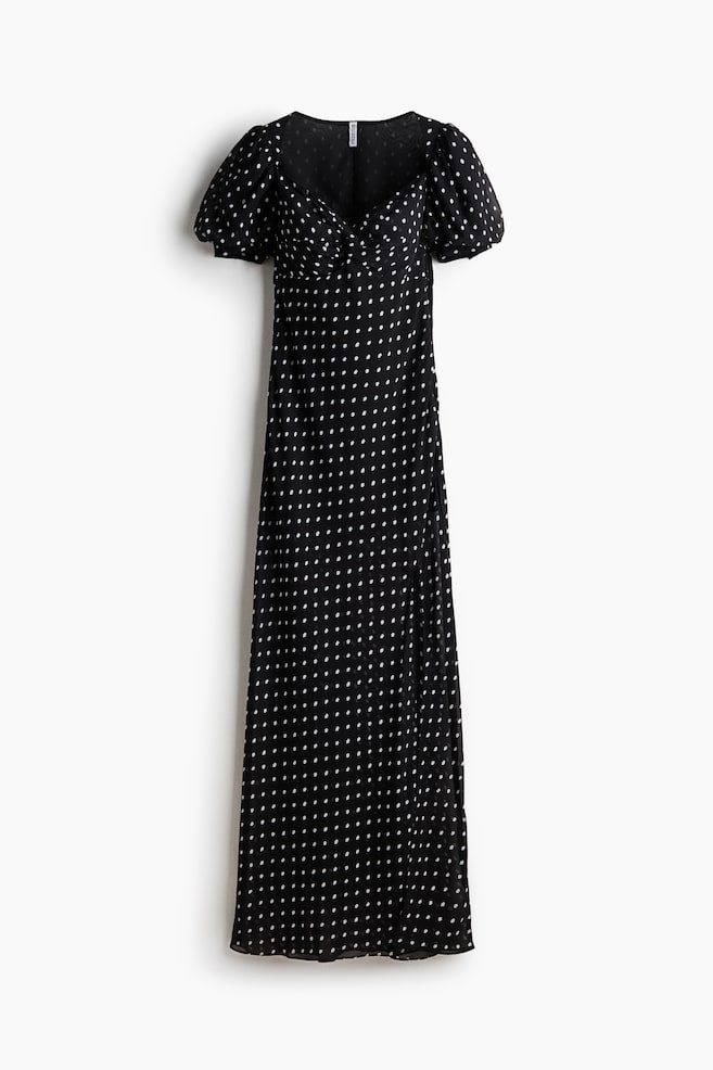 A black maxi dress with white polka dots is featuring puffed short sleeves, a V-neckline with a ruched bust, and a side slit. - 1