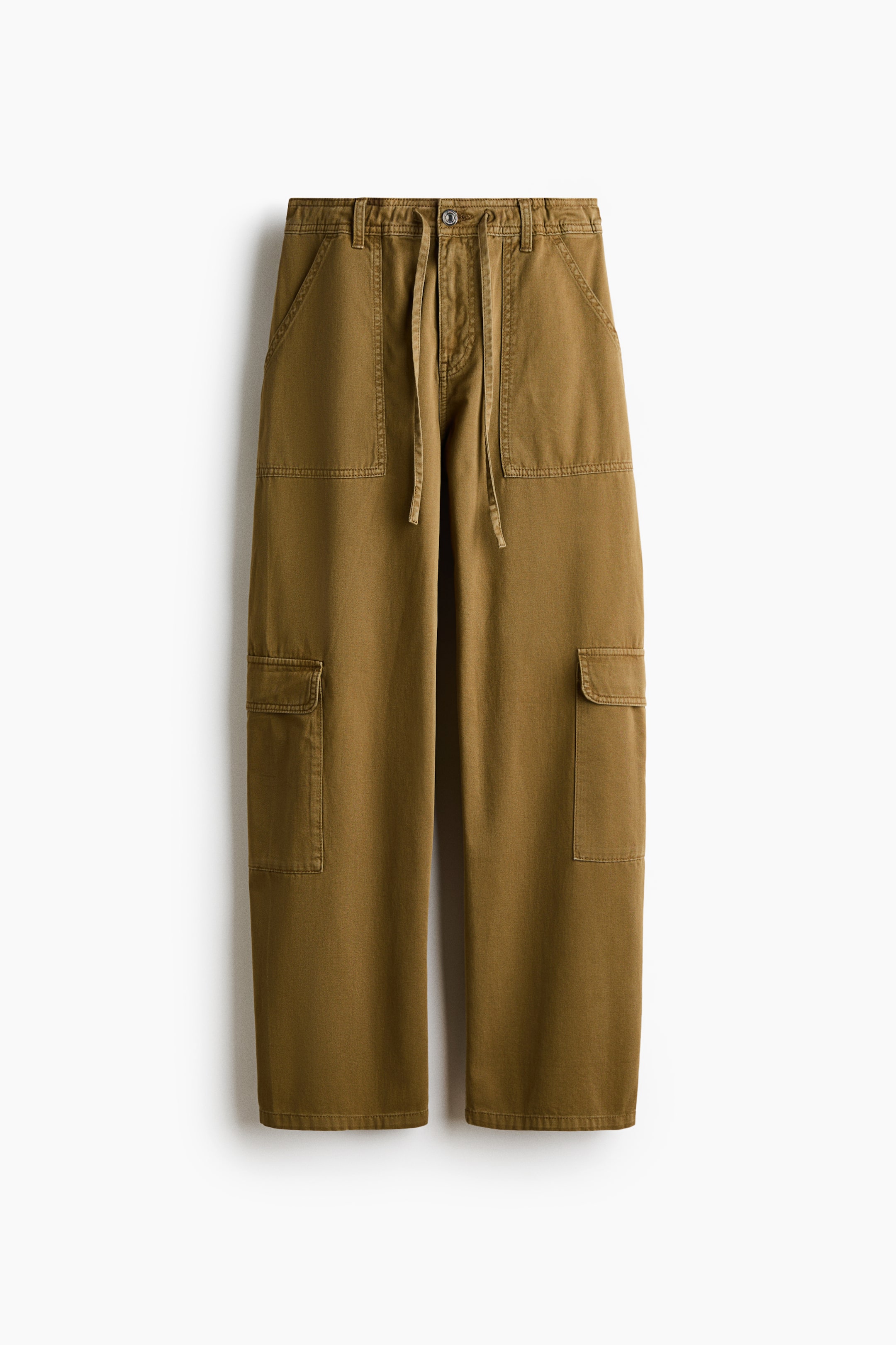View larger image: A pair of olive-brown cargo pants is hanging front-facing, featuring a straight-leg silhouette with a button-closure waistband and adjustable drawstring ties. The pants feature large patch pockets at the hips and utility-style cargo pockets with flaps on the thighs.