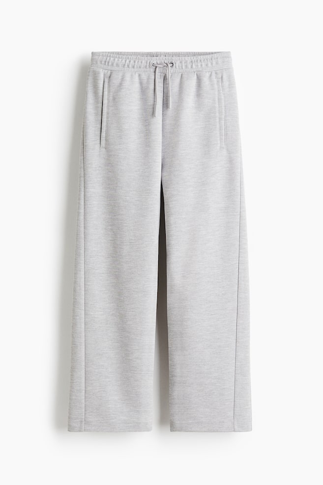 A pair of light grey sweatpants are presented from the front. They are featuring an elasticated waistband with a drawstring, two vertical front pockets, and straight legs with a visible seam running down the center front of each leg. - 1
