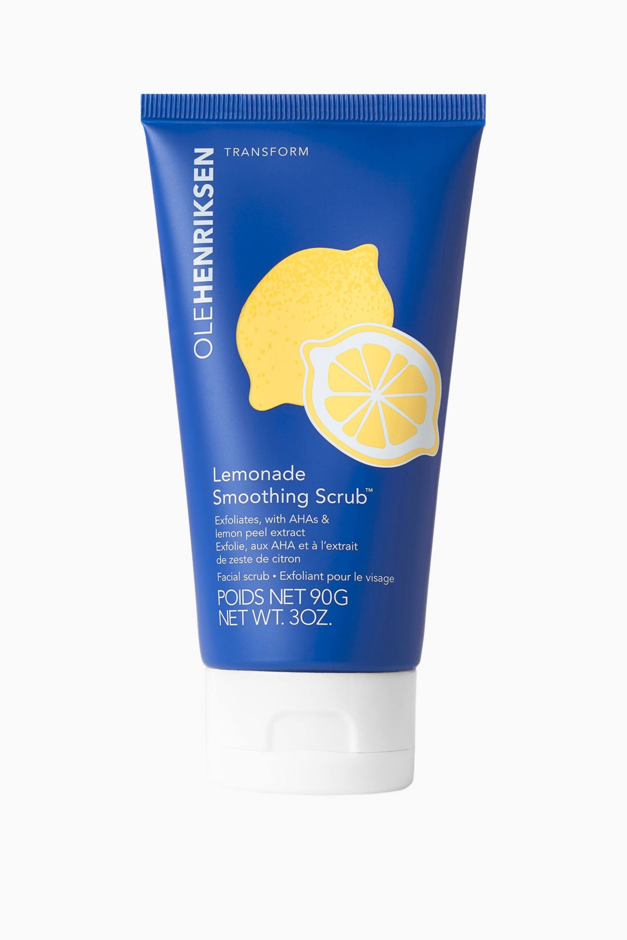 Se større billede: En tube Olehenriksen Lemonade Smoothing Scrub står oprejst og vender fremad. Den kongeblå tube har et grafisk motiv af to gule citroner, én hel og én skåret over, med brandnavnet "OLEHENRIKSEN", "TRANSFORM", produktnavnet "Lemonade Smoothing Scrub" og andre produktoplysninger trykt på forsiden, og den er afsluttet med en hvid hætte.