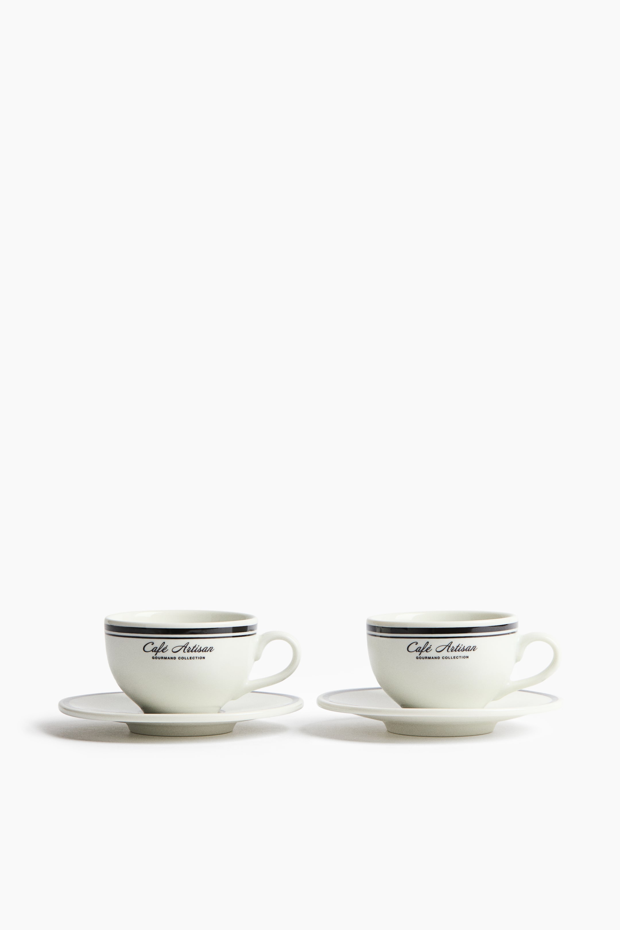 View larger image: Two white ceramic cup and saucer sets are placed facing forward. Each cup showcases a dark horizontal stripe near the rim with the text "Café Artisan GOURMAND COLLECTION" beneath it.