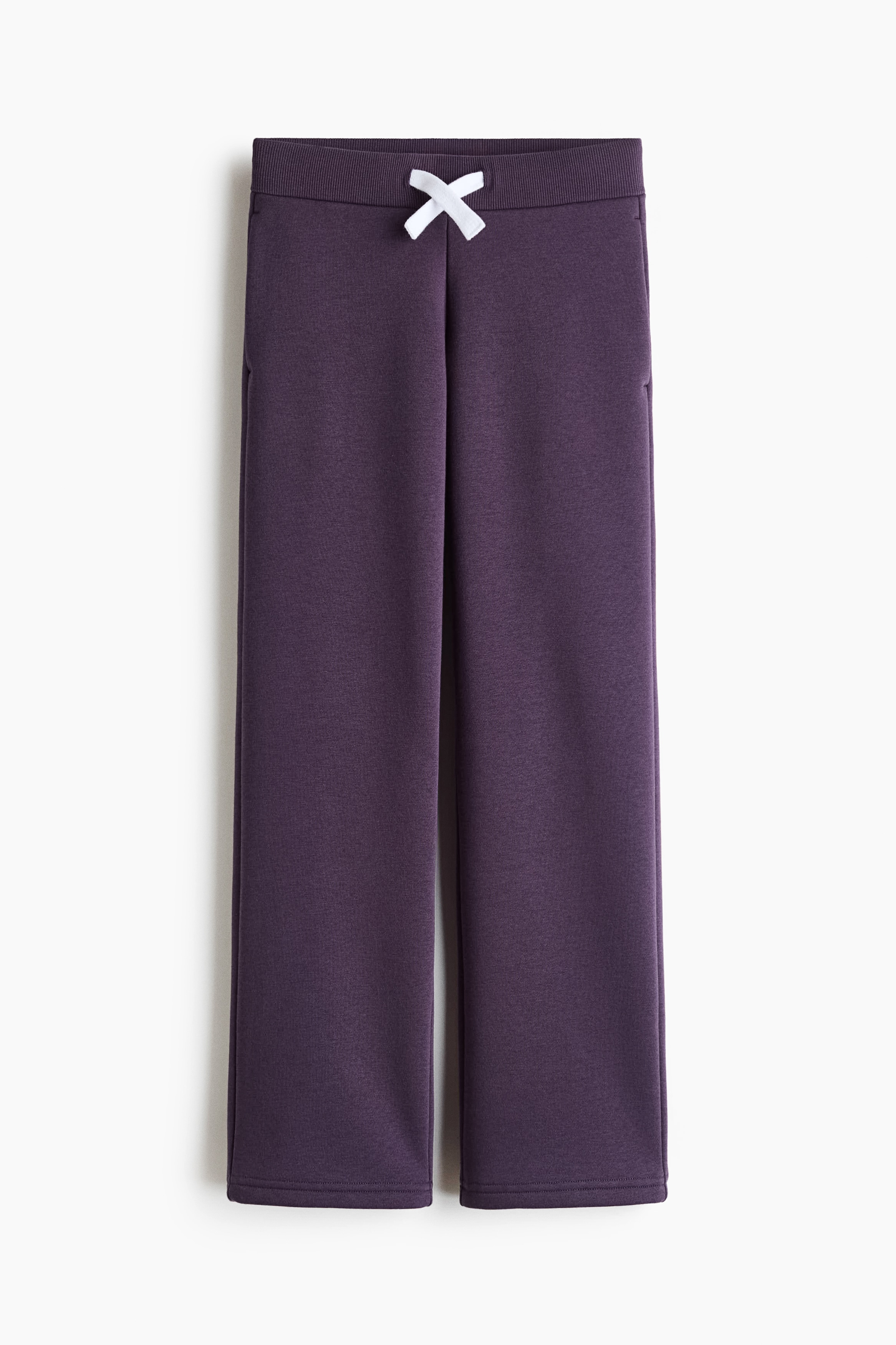 Dunkelviolette Trackpants mit weitem Bein werden an einem Model von vorne gezeigt und zeichnen sich durch eine lockere Passform sowie einen kontrastierenden, weissen Kordelzug aus, der am Bund gebunden ist. Die Hose wird mit einem in den Bund gesteckten weissen T-Shirt und weissen Sneakers gestylt, um den lÃ¤ssigen Fall und das bequeme Design hervorzuheben.