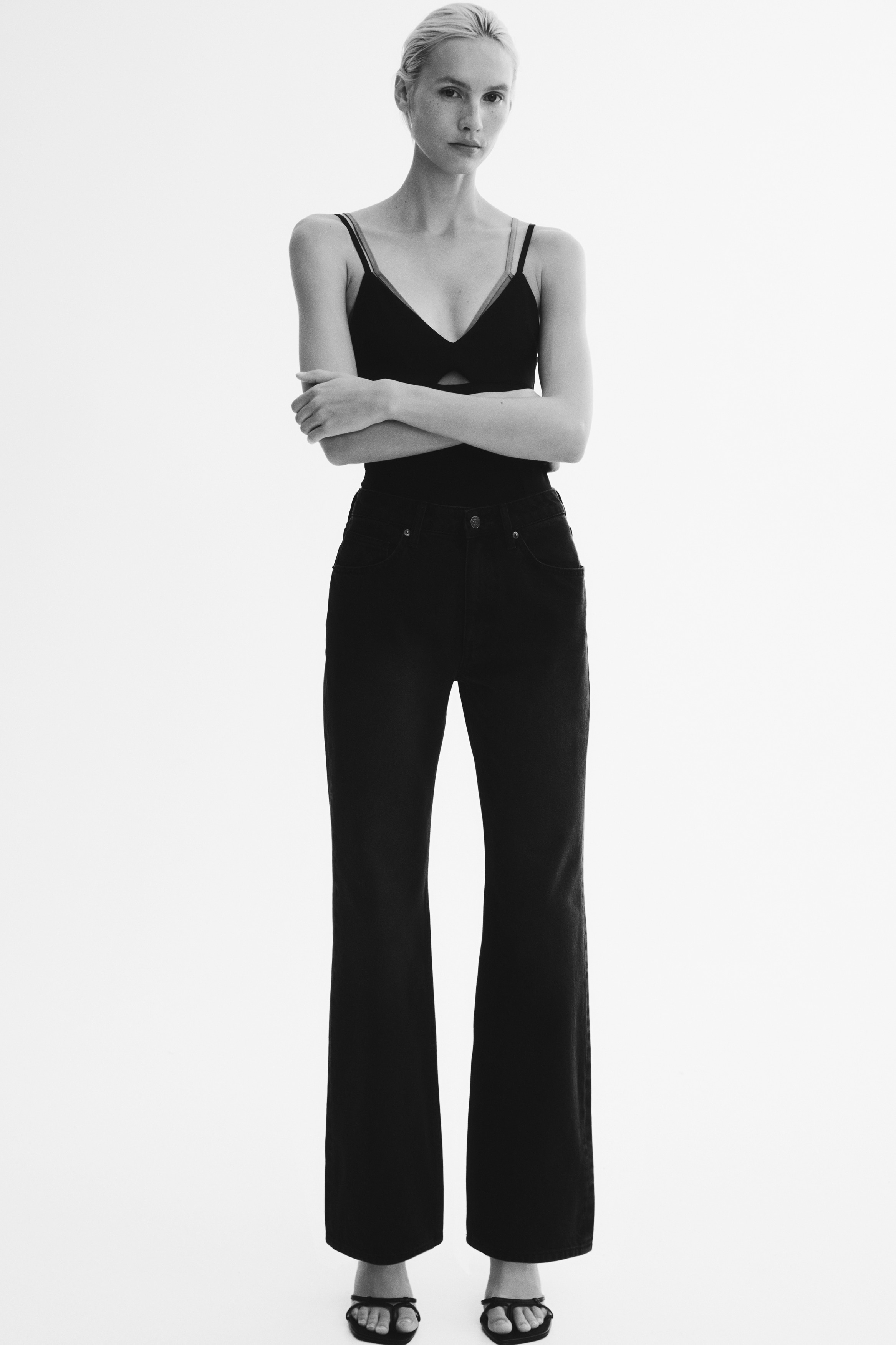 A pair of high-waisted, five-pocket jeans in faded black denim, shown from the front. The jeans feature a zip fly with a top button closure and straight-cut legs with a subtle faded wash running down the thighs.