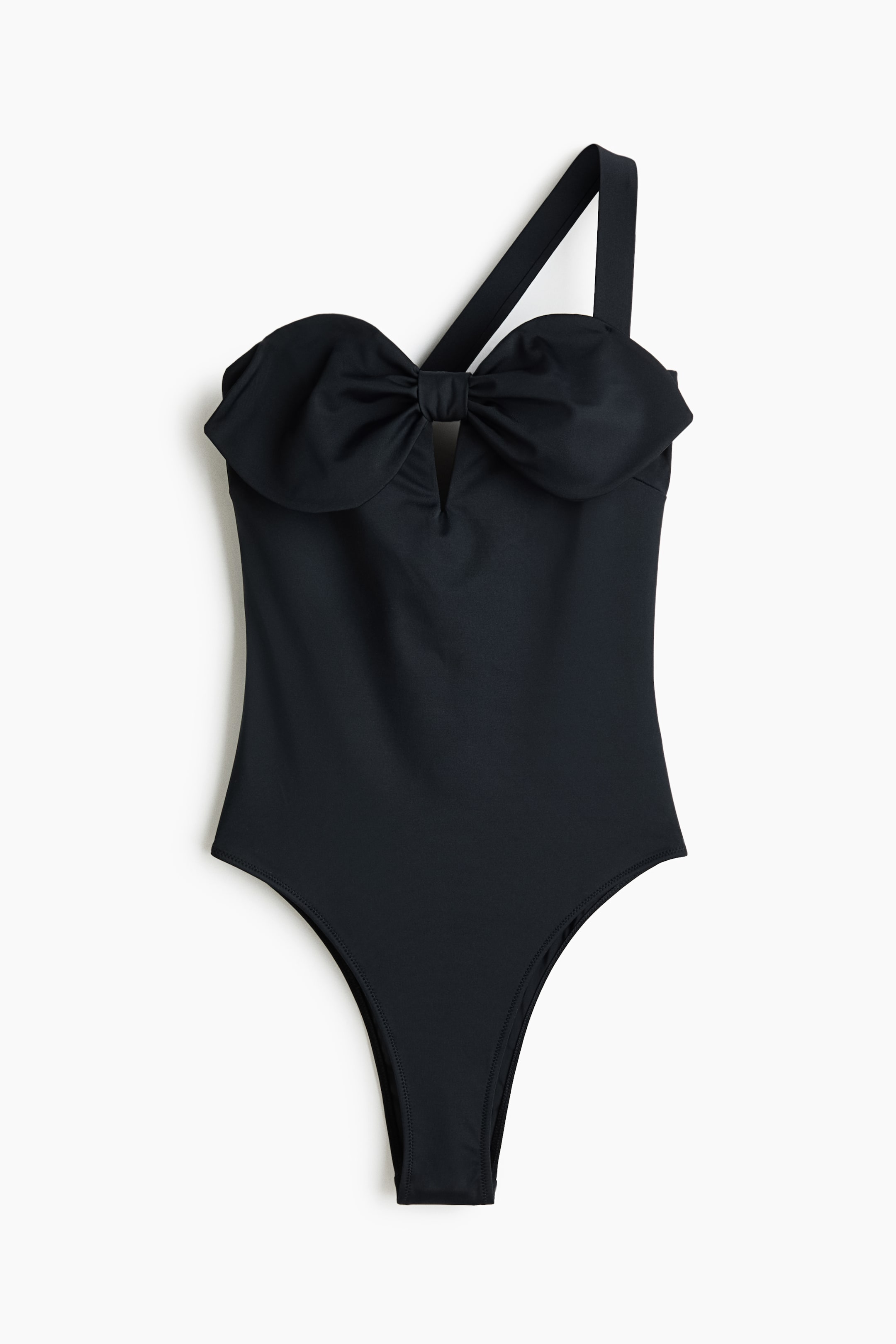 Ingrandisci l'immagine: Un costume intero nero mostra la parte anteriore, caratterizzato da un design monospalla con una spallina larga sul lato destro. Un ampio fiocco drappeggiato adorna il busto, con un piccolo intaglio a V subito sotto, e il costume presenta aperture per le gambe ad alto taglio.