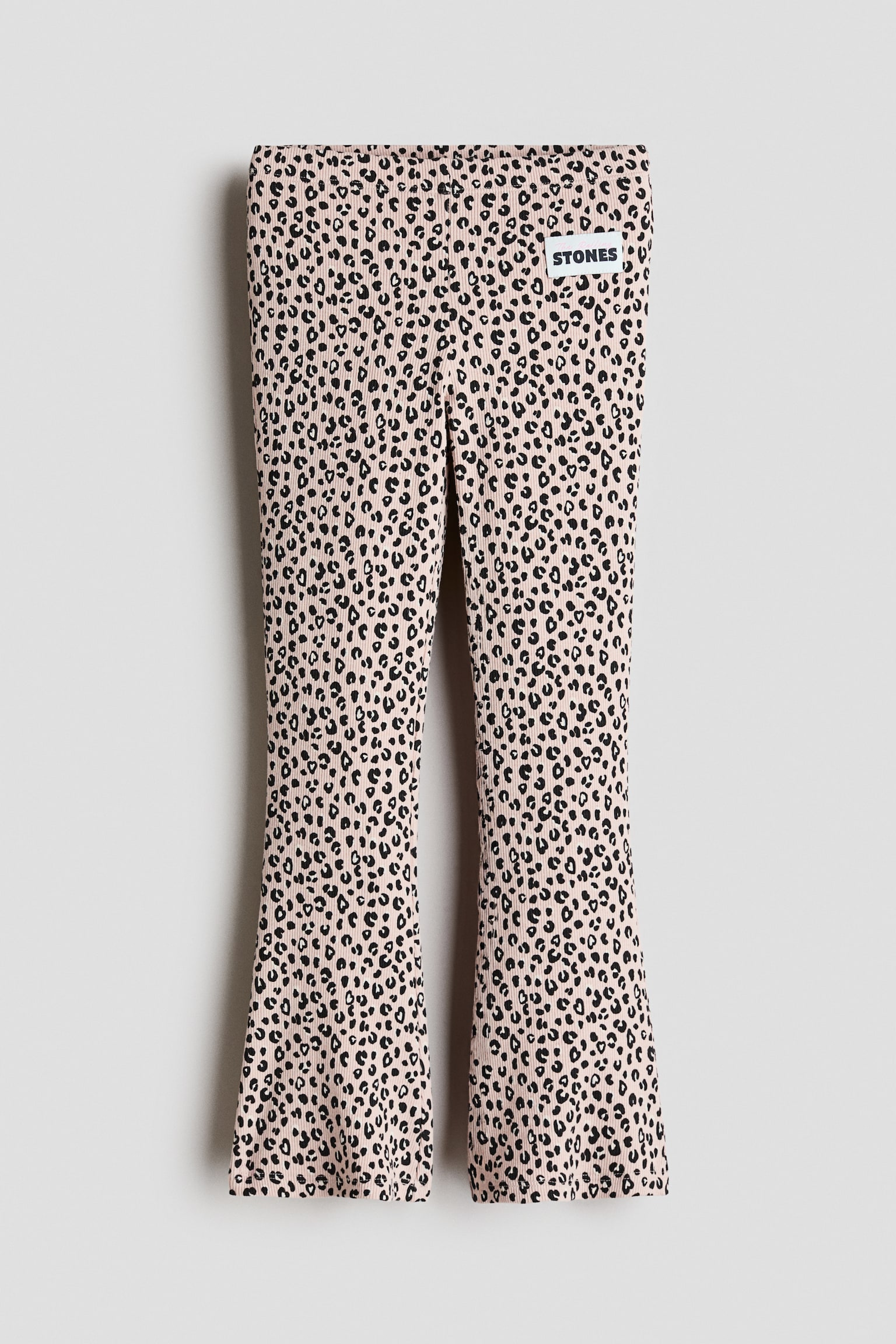 Hellrosa gerippte Schlaghose, von vorne gezeigt, mit durchgehendem schwarzem Leopardenmuster und einer eng anliegenden Silhouette, die zum Saum hin weiter wird. Die Hose hat einen flachen Bund und einen kleinen weiÃen rechteckigen MarkenaufnÃ¤her am oberen linken Oberschenkel.