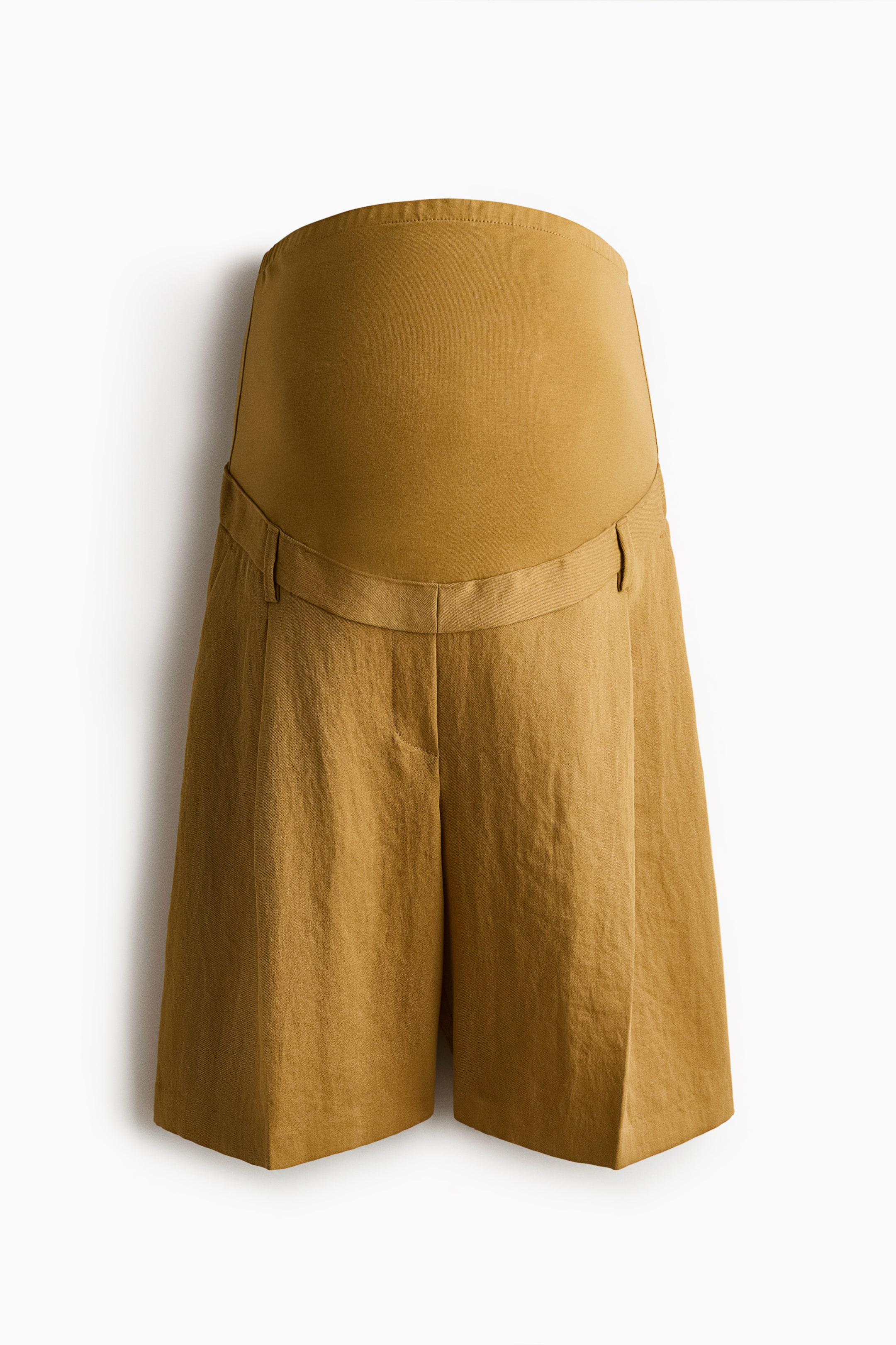 Visa större bild: Ockrafärgade knälånga vävda shorts visar en lös passform framifrån, med veck och veck längs benen. En bred jersey-panel sträcker sig uppåt från midjan, och shortsen har täckt elastik i sidorna av midjan, med diagonala sidofickor synliga nedanför en falsk gylf.