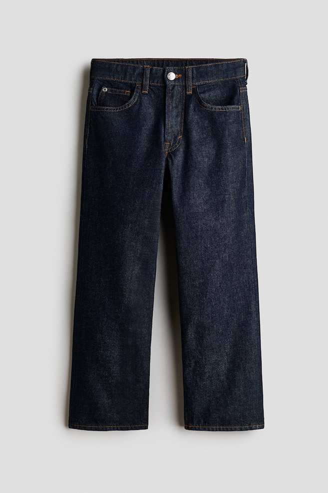 These dark blue denim jeans are shown from the front, featuring a loose-fit, straight-leg silhouette with classic orange contrast stitching. The design displays a five-pocket construction, belt loops, and a single metal button closure at the waistband. - 1