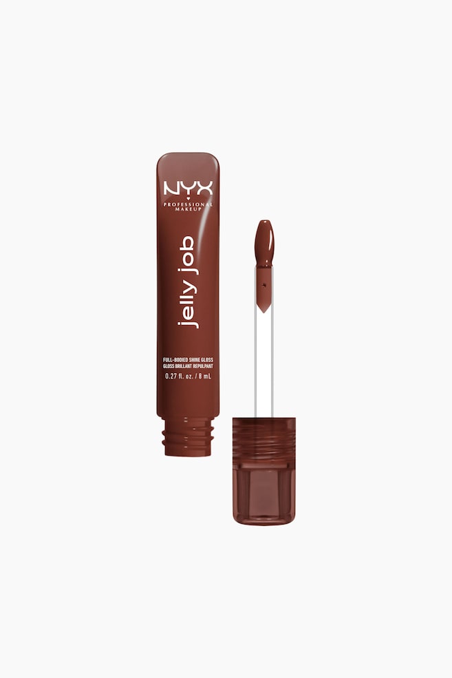 En NYX Professional Makeup "jelly job" full-bodied shine-gloss i en dyp rødbrun nyanse står oppreist. Applikatoren, med en doe-foot-tupp dekket av glossen, ligger ved siden av den åpne tuben, og den avskrudde korken er synlig. - 1