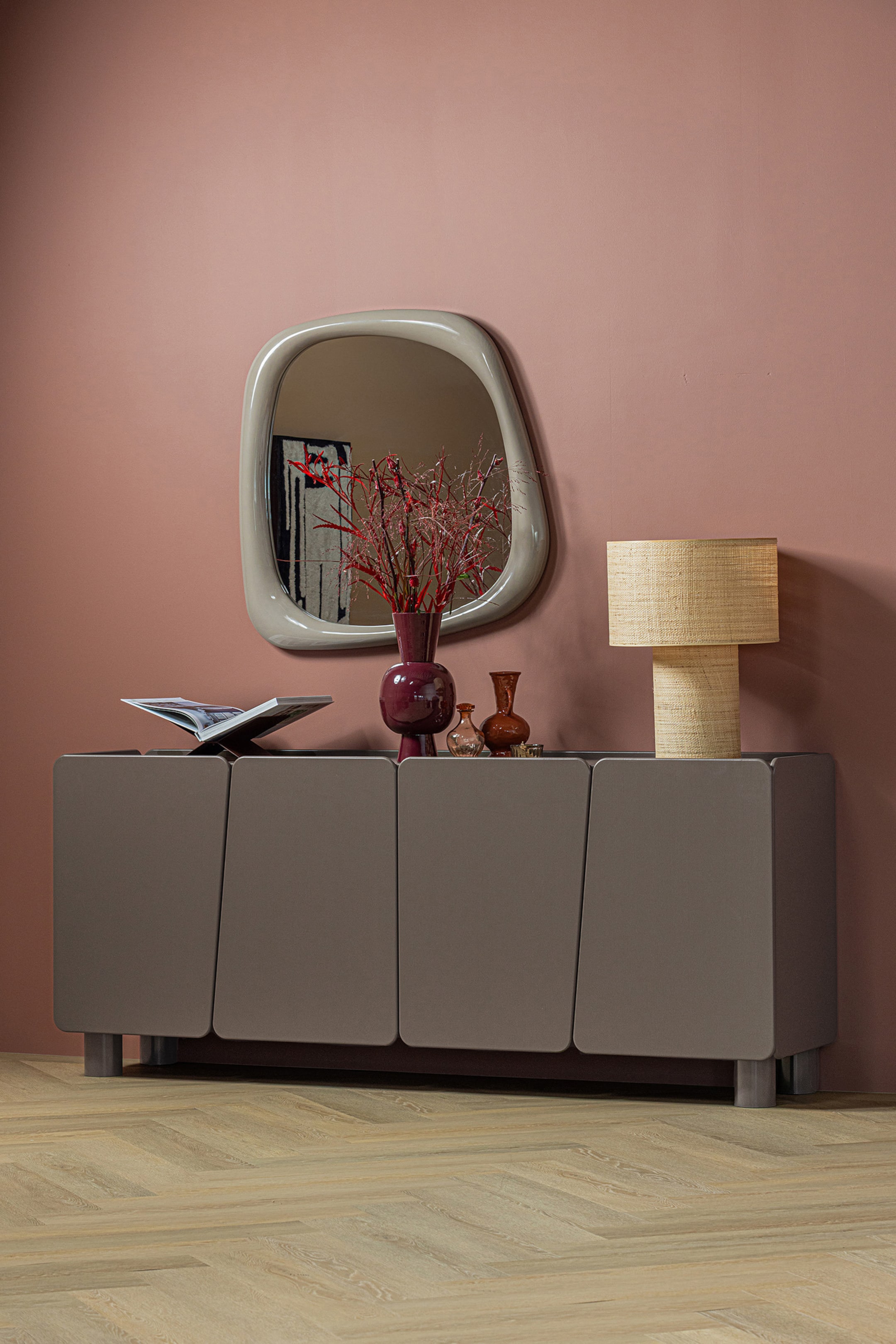Agrandir l'image: Le buffet gris est doté d'une surface supérieure plane et de quatre portes affleurantes, chacune présentant un design de panneau subtilement incliné. Il repose sur de courtes jambes cylindriques et est légèrement orienté vers la droite.