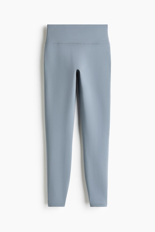 Un par de leggings de tiro alto color azul claro se muestra en vista frontal, con una cintura ancha y una silueta lisa y ajustada que se estrecha hasta los tobillos. - 1