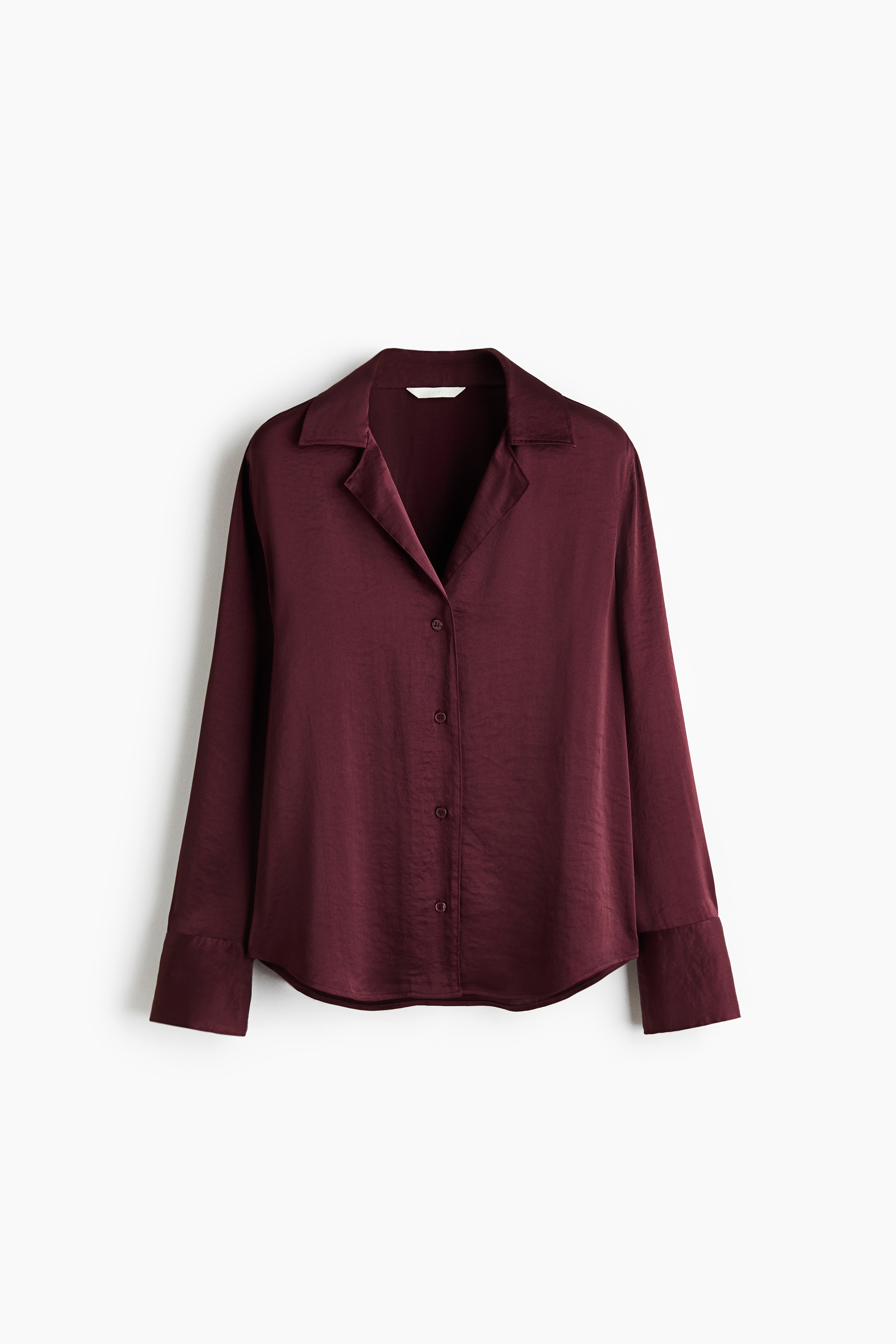 A burgundy satin shirt is hanging facing forwards, showcasing a relaxed resort collar, a button-down front fastening, and long sleeves with wide cuffs. The shirt displays a softly draping texture and is finished with a gently rounded hem.