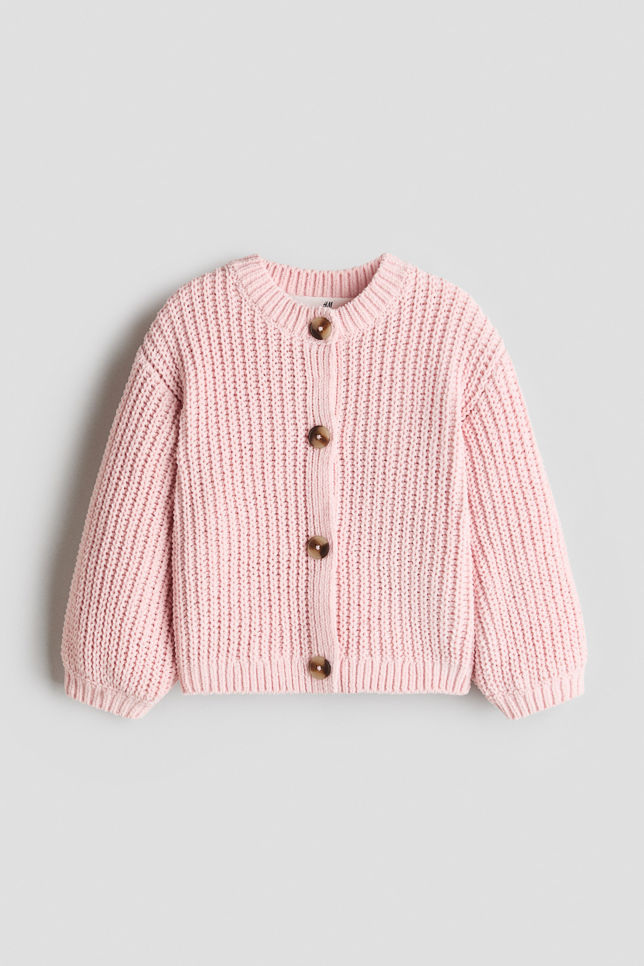 View larger image: A light pink chunky knit cardigan is neatly showcased with a ribbed crew neck, hem, and cuffs on its long sleeves, featuring four brown buttons fastening the front.