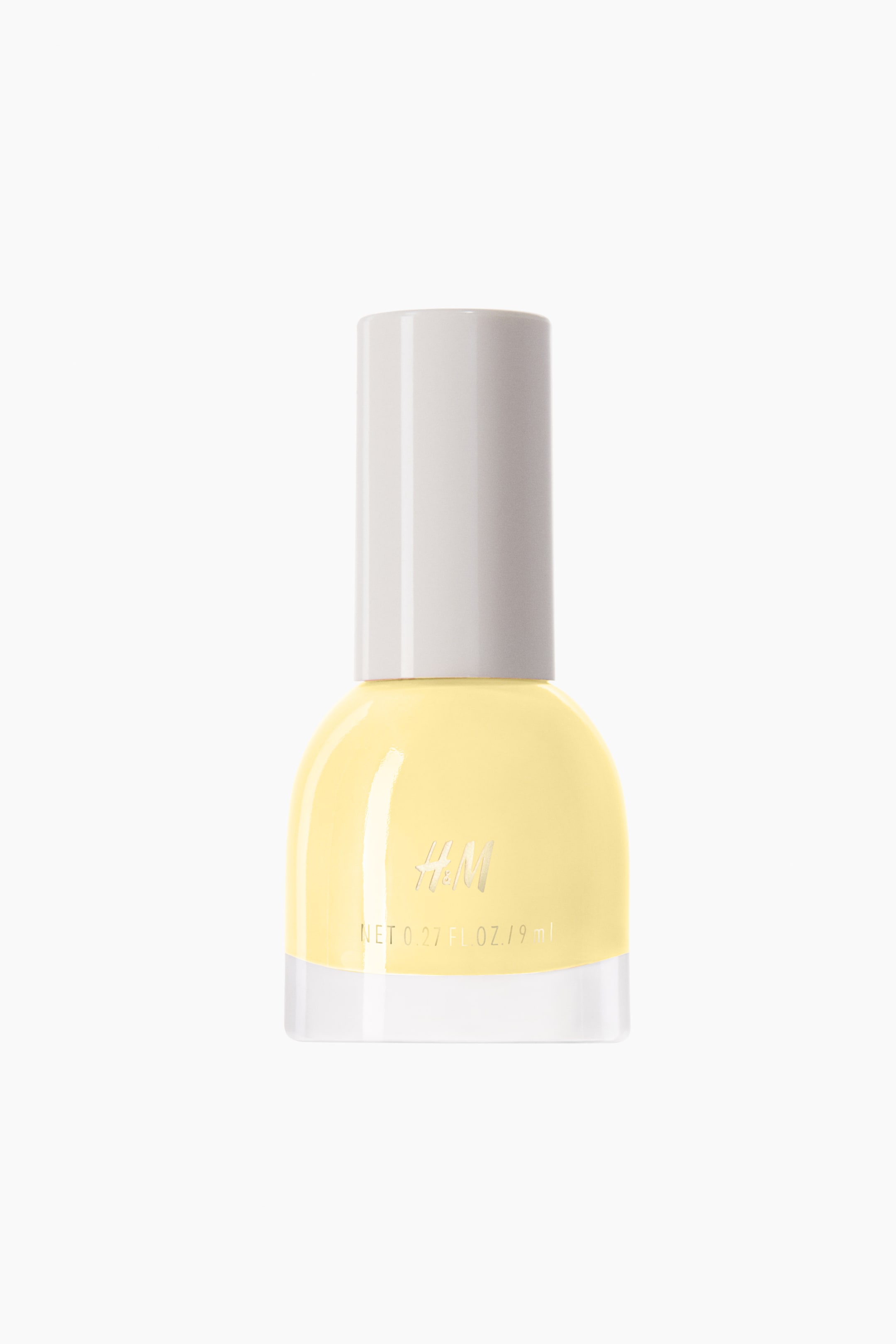 View larger image: A yellow nail polish bottle is standing upright, showcasing a clear glass base, rounded shoulders, and a light grey cylindrical cap. The 'H&M' logo and 'NET 0.27 FL. OZ. / 9 ml' text are visible on the front of the bottle.