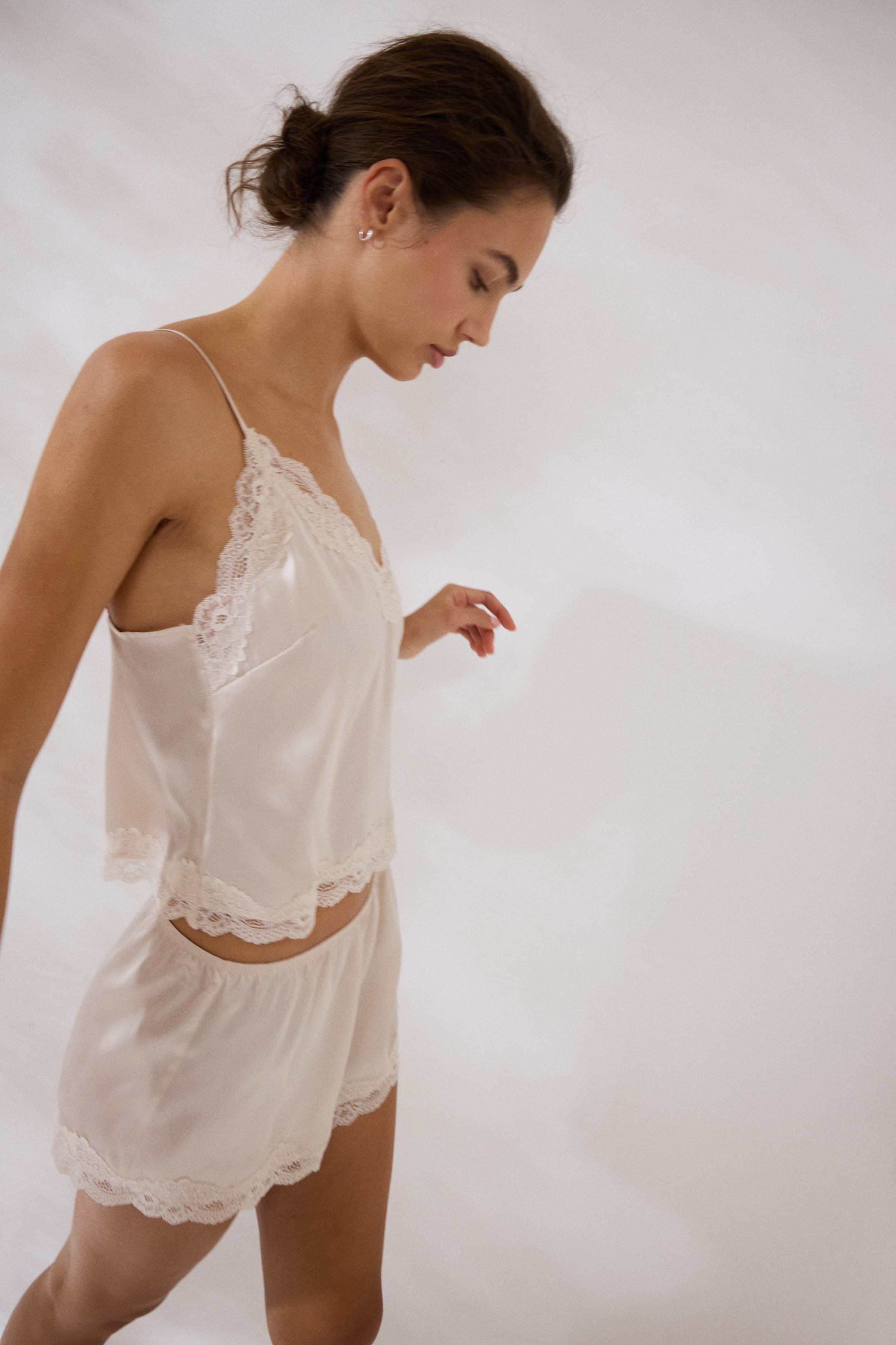 Prikaži veću sliku: Set od satena u boji rumenila, koji se sastoji od kamisol majice i šortseva, prikazan je iz desnog, ugaonog bočnog pogleda. Kamisol majica ima tanke špageti bretele i čipkaste ivice duž V-izreza i poruba, dok šortsevi imaju elastičan pojas i čipkaste ivice duž otvora za noge.