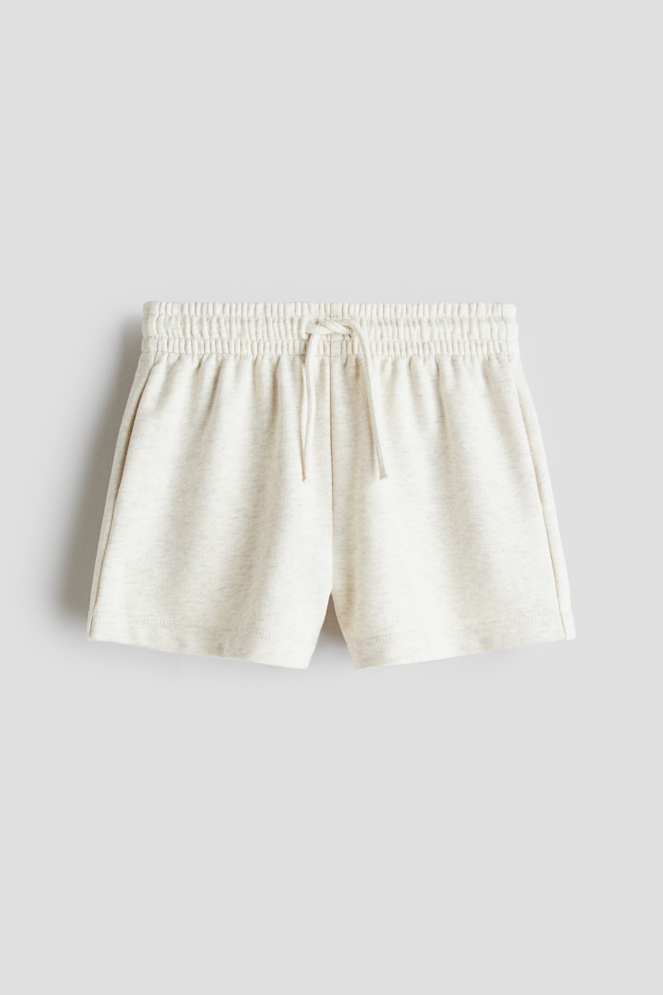 View larger image: "The light beige heathered shorts are shown from a front view, showcasing an elasticized waistband with a central drawstring tie. Two angled front pockets are visible on the sides."