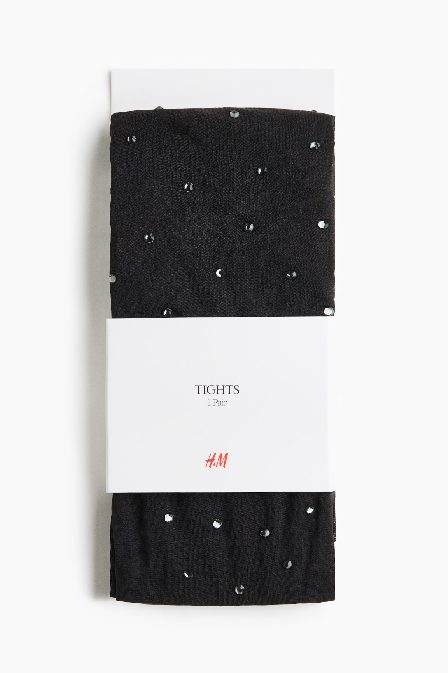 A front view of a packaged pair of folded black tights featuring scattered, sparkling rhinestones across the semi-sheer fabric. The tights are wrapped around a white cardboard insert and secured with a white paper band displaying the brand logo and product details.