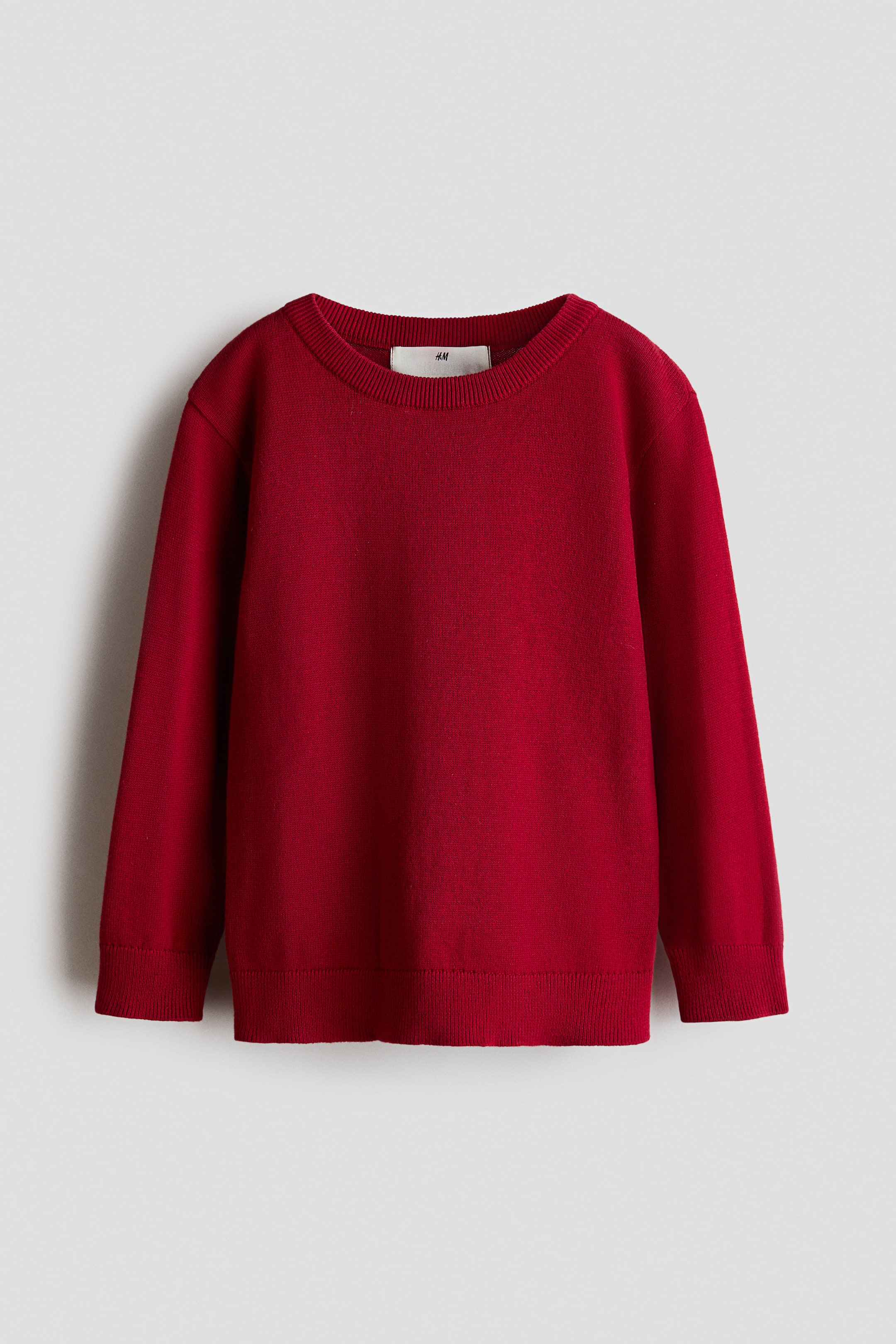 View larger image: A red fine-knit cotton sweater is shown front-facing, featuring a round rib-trimmed neckline, long sleeves with ribbed cuffs, and a ribbed hem.