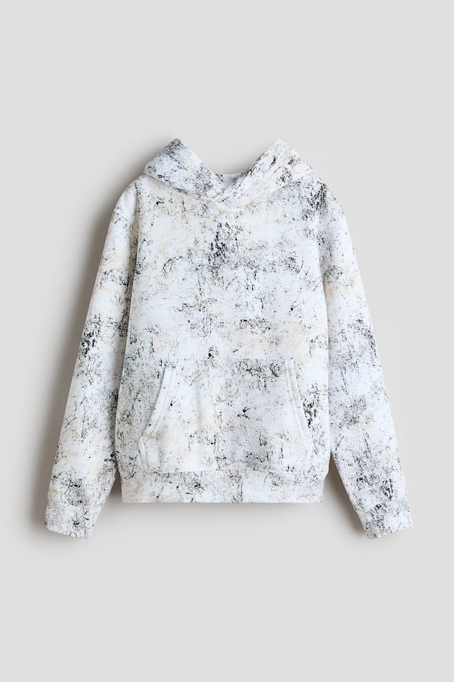 A hoodie is displaying its front, featuring a white base with an all-over abstract black and beige mottled pattern. It is designed with a hood, long sleeves with ribbed cuffs, a kangaroo pocket, and a ribbed hem. - 1