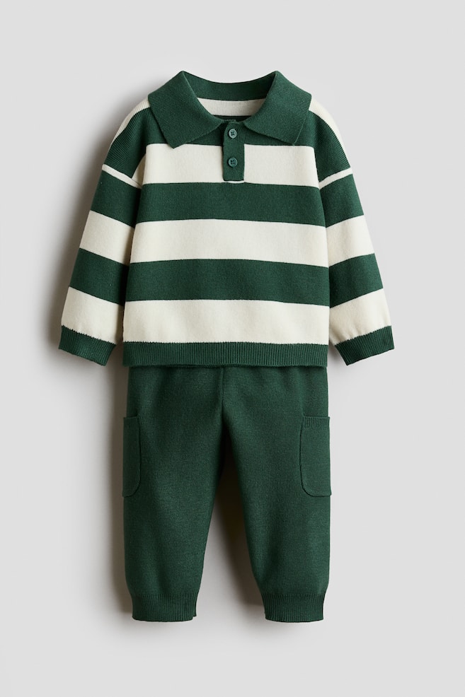 A front-facing knitted sweater and trousers set showcases a green and cream horizontally striped sweater paired with solid green trousers. The sweater features a collar, a two-button placket, dropped shoulders, and ribbed cuffs and hem, whilst the trousers feature patch pockets on the legs and ribbed ankle cuffs. - 1