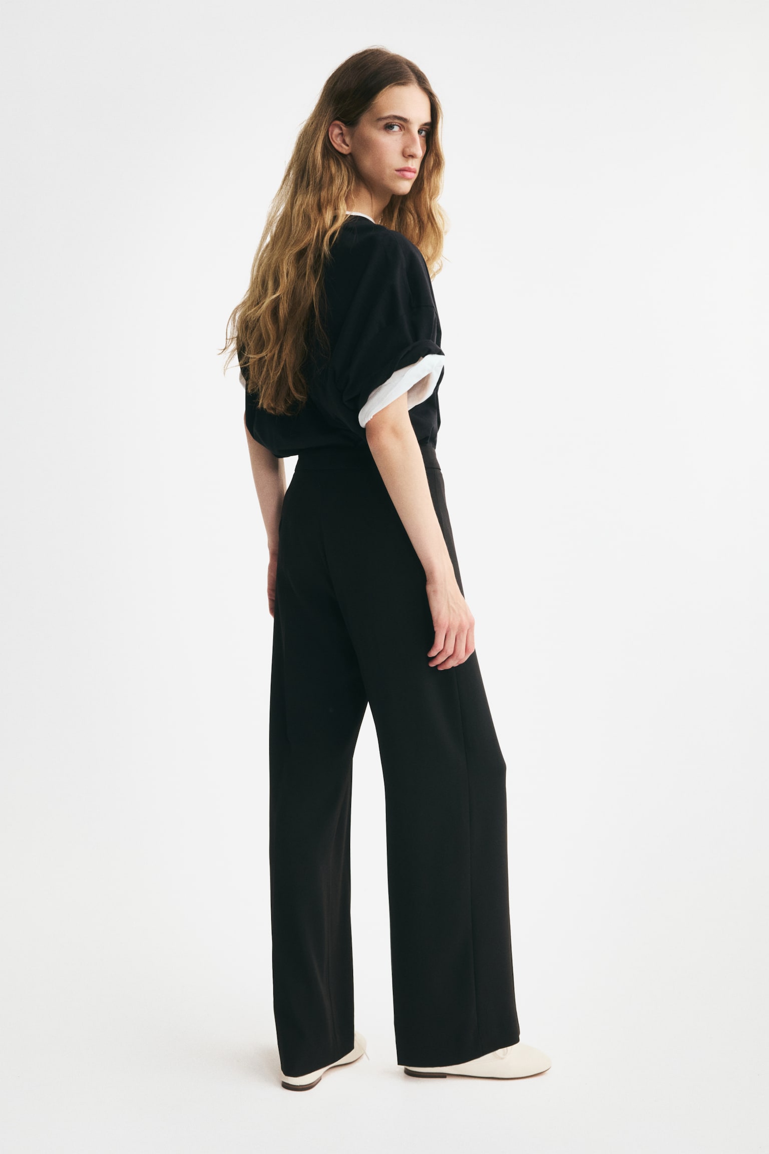 Black trousers are featuring a flat waistband and sharp vertical creases running down the center of each straight leg, as viewed from the front. - 1
