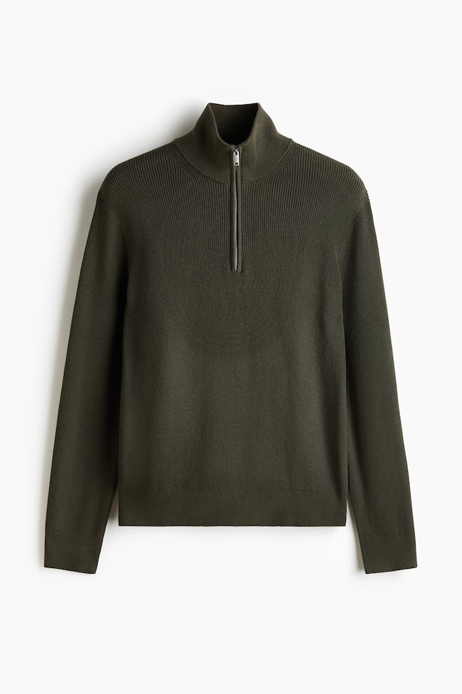 A dark green quarter-zip jumper is facing front, featuring a ribbed mock neck with a partially unzipped silver-toned zip. The upper body displays a prominent ribbed knit, while the lower body and long sleeves showcase a finer knit with ribbed cuffs and hem. - 1