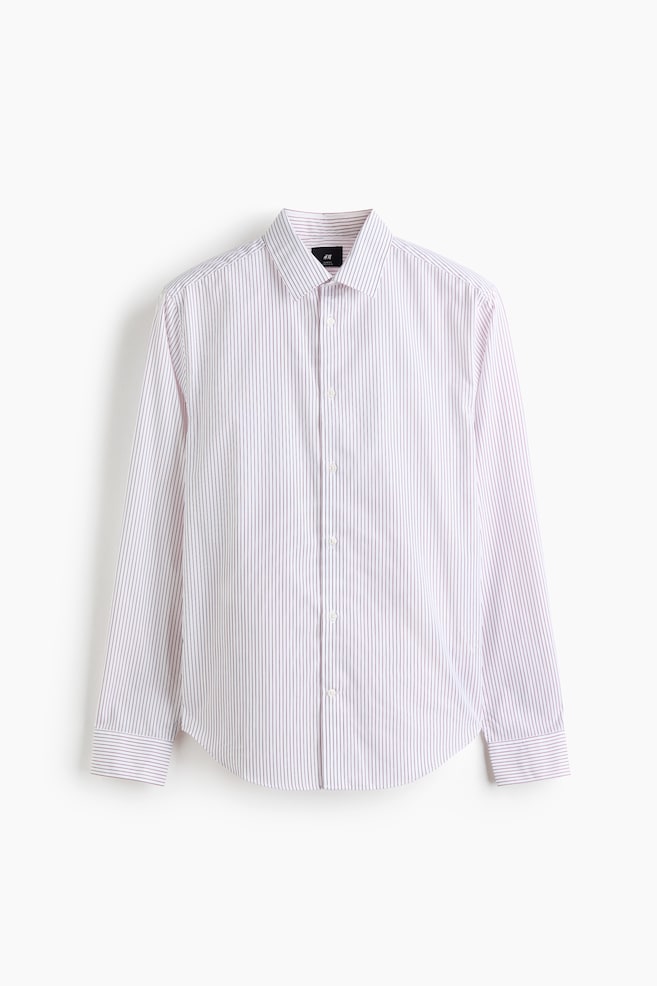 A long-sleeved woven shirt featuring thin, vertical red and white stripes is shown facing forwards. The shirt features a classic turn-down collar, a button-up front, and a gently rounded hem. - 1