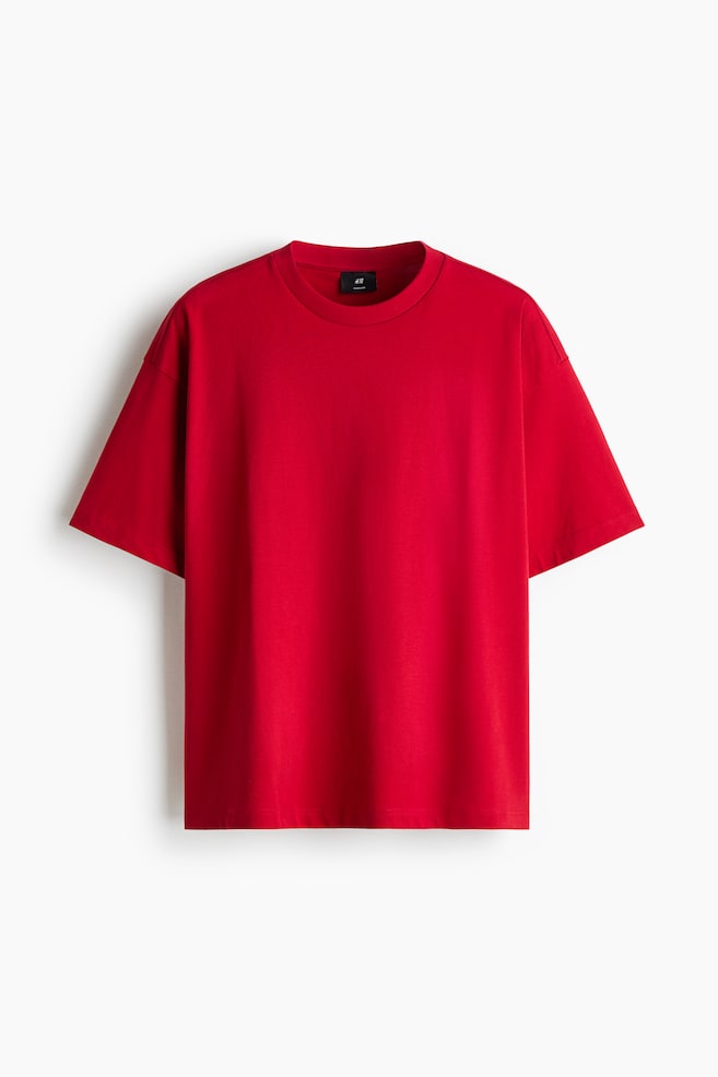 Een rood, boxy, oversized T-shirt van katoenjersey hangt frontaal en laat een geribde ronde hals, verlaagde schouders en een rechte zoom zien. Het kledingstuk heeft een extra losse silhouet met wijde, korte mouwen. - 1
