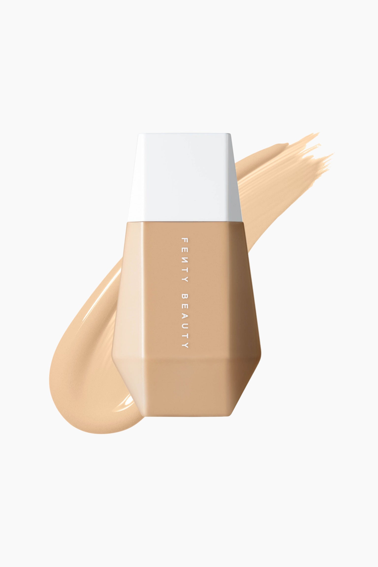 En flaska Fenty Beauty Eaze Drop Blurring Skin Tint stÃ¥r upprÃ¤tt i en framifrÃ¥n-vy och Ã¶verlappar ett diagonalt streck av ljus-medium beige flytande foundation. Den mÃ¥ngfacetterade, kantiga flaskan har ett platt vitt lock och vertikal vit text som lyder "FENTY BEAUTY" ned lÃ¤ngs mitten.