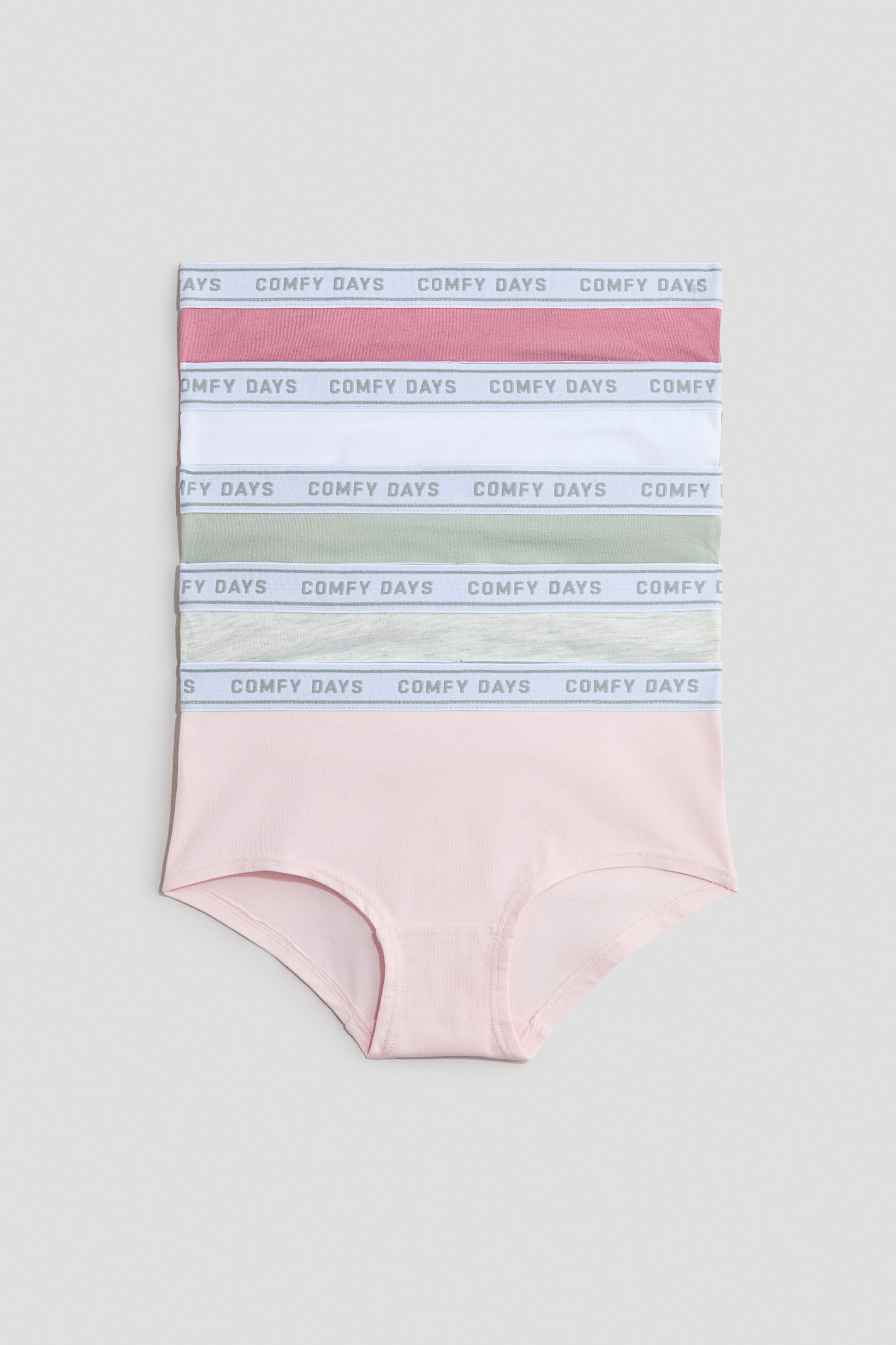 View larger image: A set of five women's briefs is showcased, each with elastic waistbands that have the 'COMFY DAYS' text. The briefs come in maroon, white, sage green, light grey, and light pink, with the bottom light pink brief featuring a classic cut.