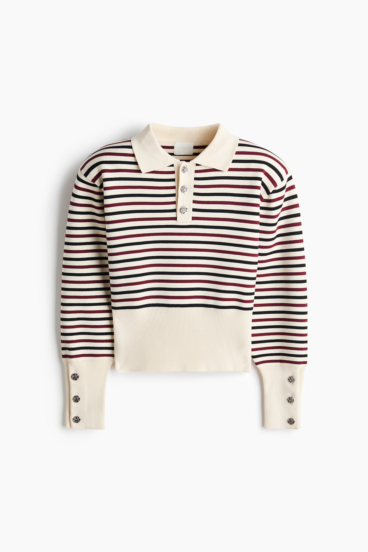 A short fine-knit polo shirt is shown from the front in a cream base with horizontal black and burgundy stripes. It features a classic collar, a three-button placket with decorative metallic buttons, and structured shoulders. The long sleeves finish in wide, buttoned ribbed cuffs that match a wide, solid cream ribbed hem. - 1