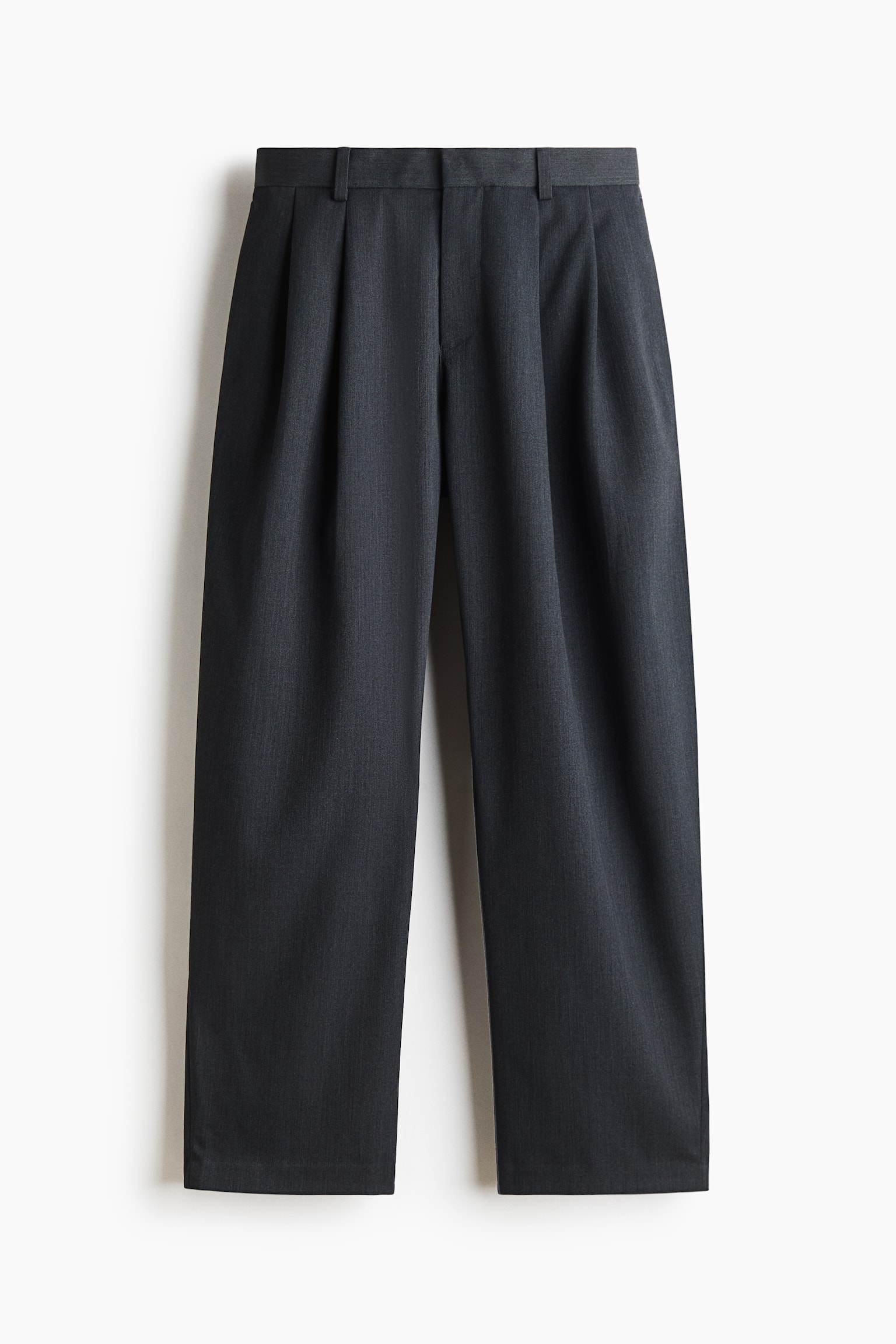 Un paio di pantaloni pieghettati grigio scuro Ã¨ mostrato frontalmente, con una vita strutturata con passanti per cintura e doppie pince anteriori che cadono in una vestibilitÃ  ampia e rilassata.