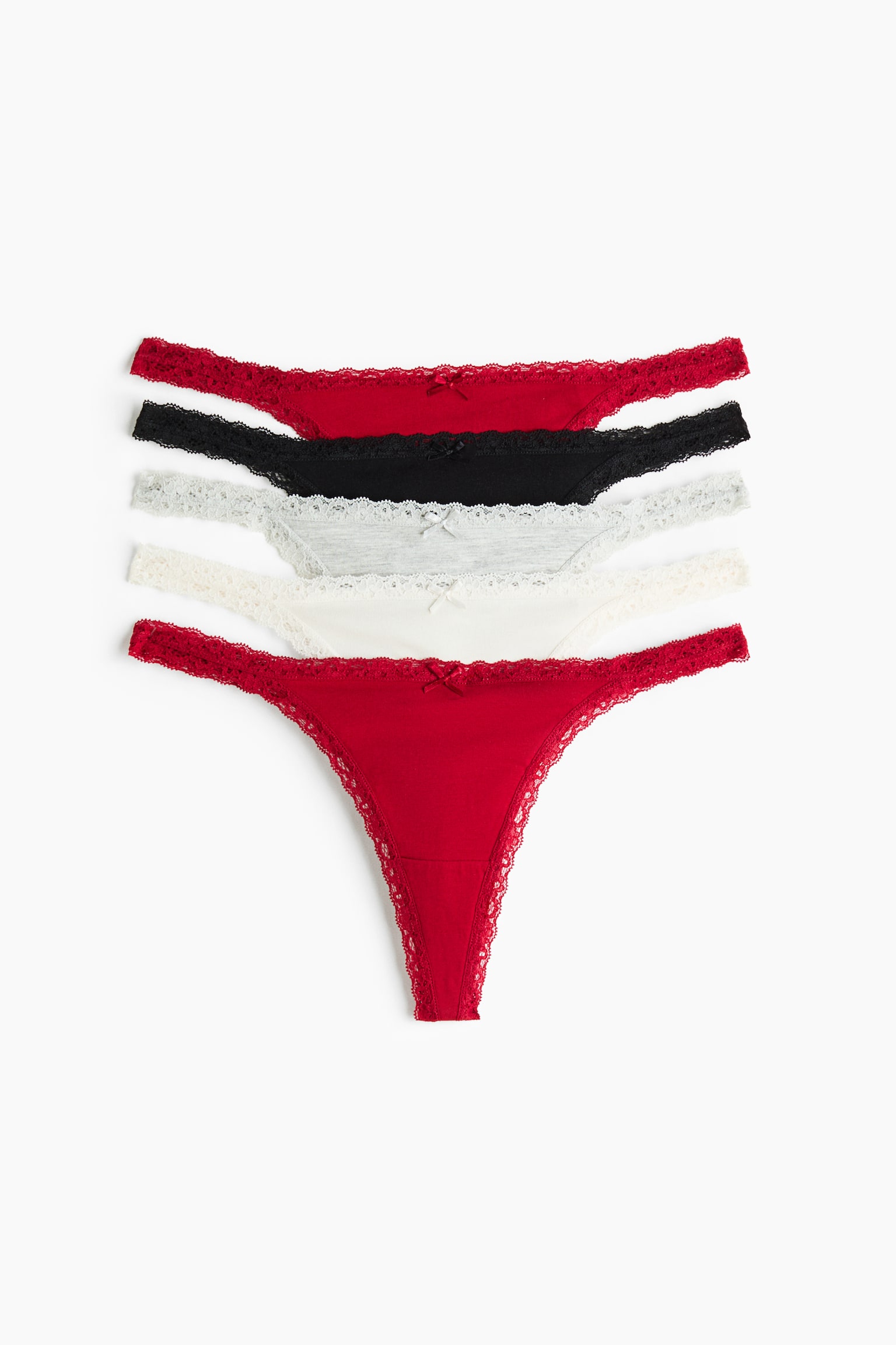 Ett set med fem G-strÃ¤ngar i bomullsjersey ligger plant framifrÃ¥n i en staplad arrangemang, dÃ¤r ett par i klarrÃ¶tt framtrÃ¤der i fÃ¶rgrunden med par i svart, grÃ¥tt, krÃ¤mfÃ¤rgat och mÃ¶rkrÃ¶tt lager bakom. Varje par har en lÃ¥g midja med fina spetskanter och en liten dekorativ rosett mitt fram.
