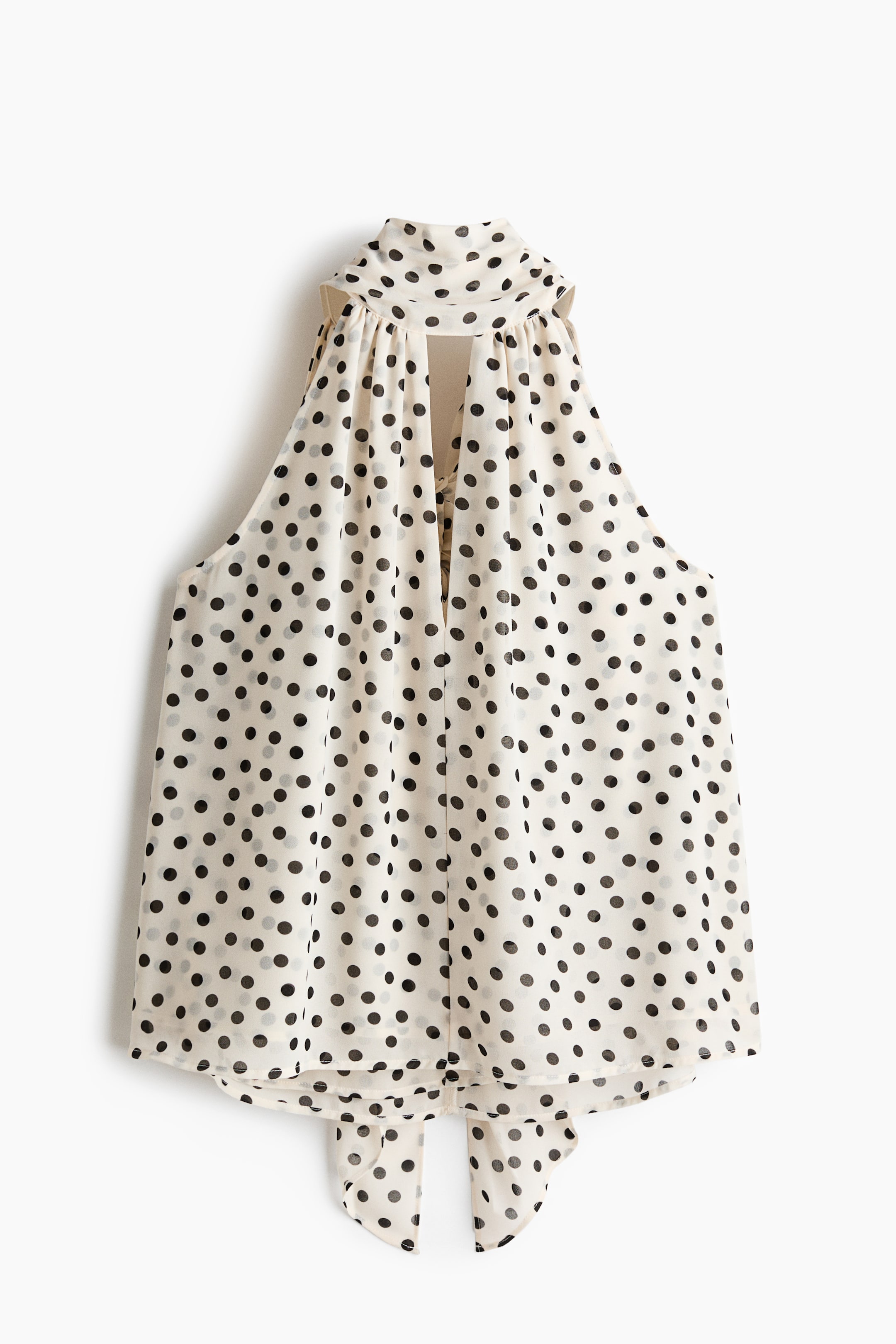 View larger image: The front of the cream-and-black polka-dot sleeveless top features a gathered high neck with a keyhole opening below. It presents a flowing silhouette, a rounded hem and two ties at the back hem.
