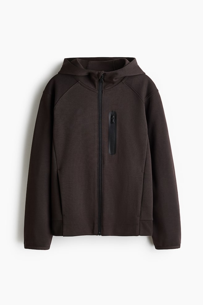 A dark brown hooded jacket is showing its front, with a full black zipper closure running down the center. A vertical black zippered pocket is appearing on the left chest, and raglan seams are defining the shoulders. - 1
