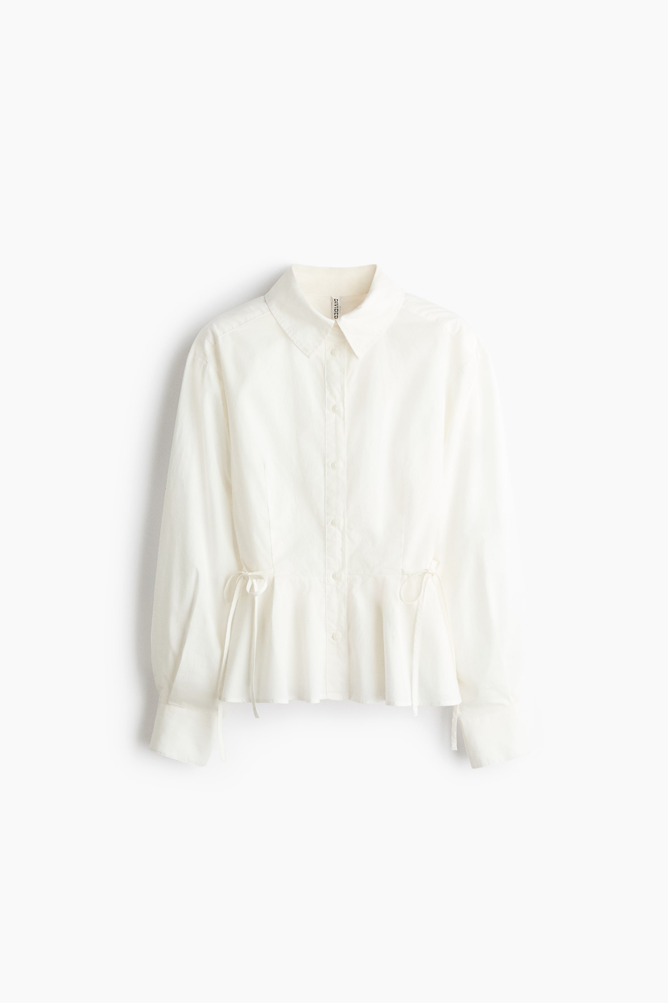 View larger image: A white, long-sleeved button-down shirt is shown from the front, featuring a classic collar, a buttoned front placket, and wide cuffs. The shirt is designed with a cinched waist featuring adjustable side drawstrings that tie into bows, creating a flared peplum hem.