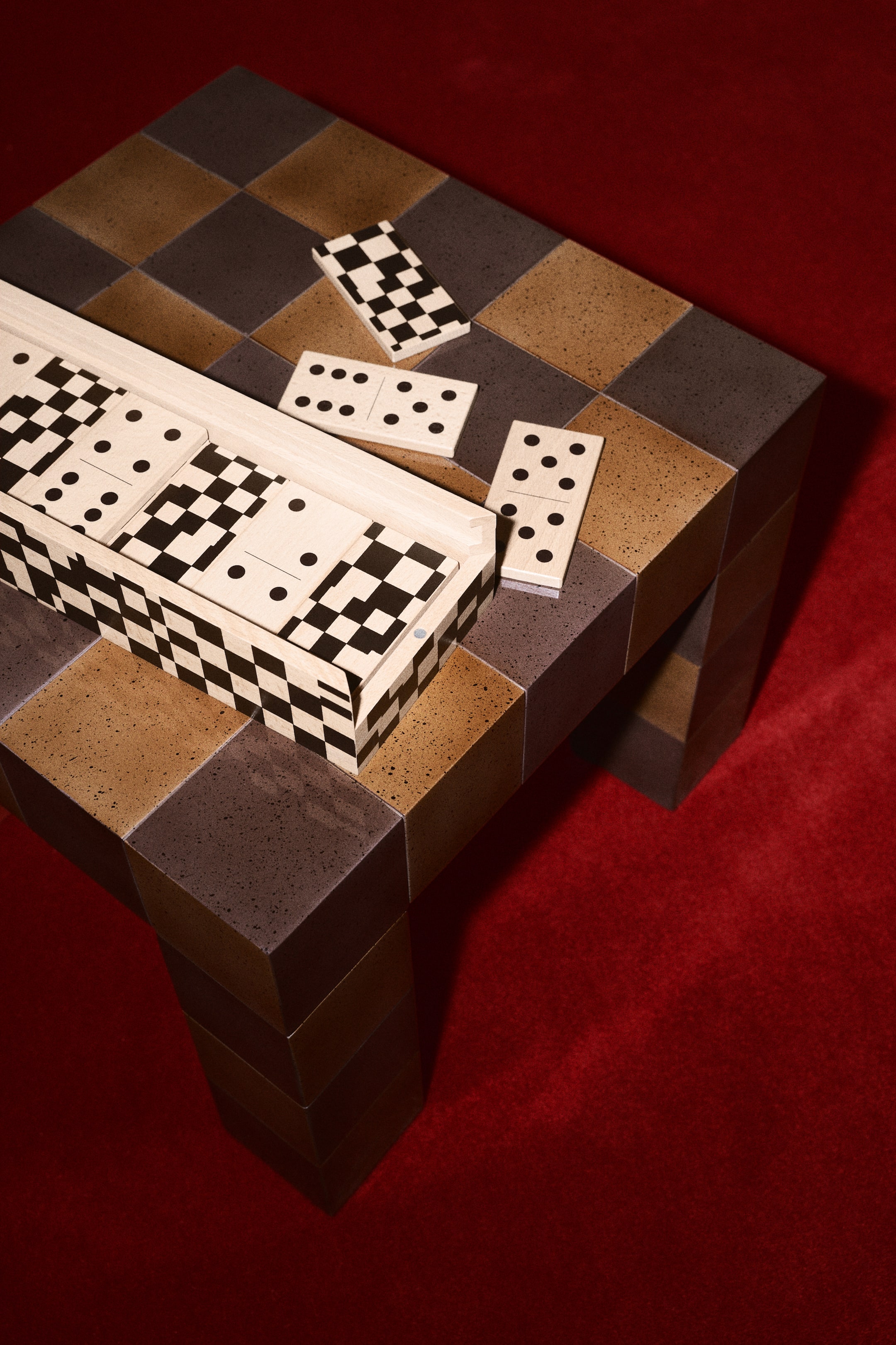 View larger image: A classic set of pinewood dominoes is displayed, with numerous tiles showcasing black dots and checkerboard backs. The game is elegantly arranged in an open, printed box, adorned with a black and white checkerboard pattern.