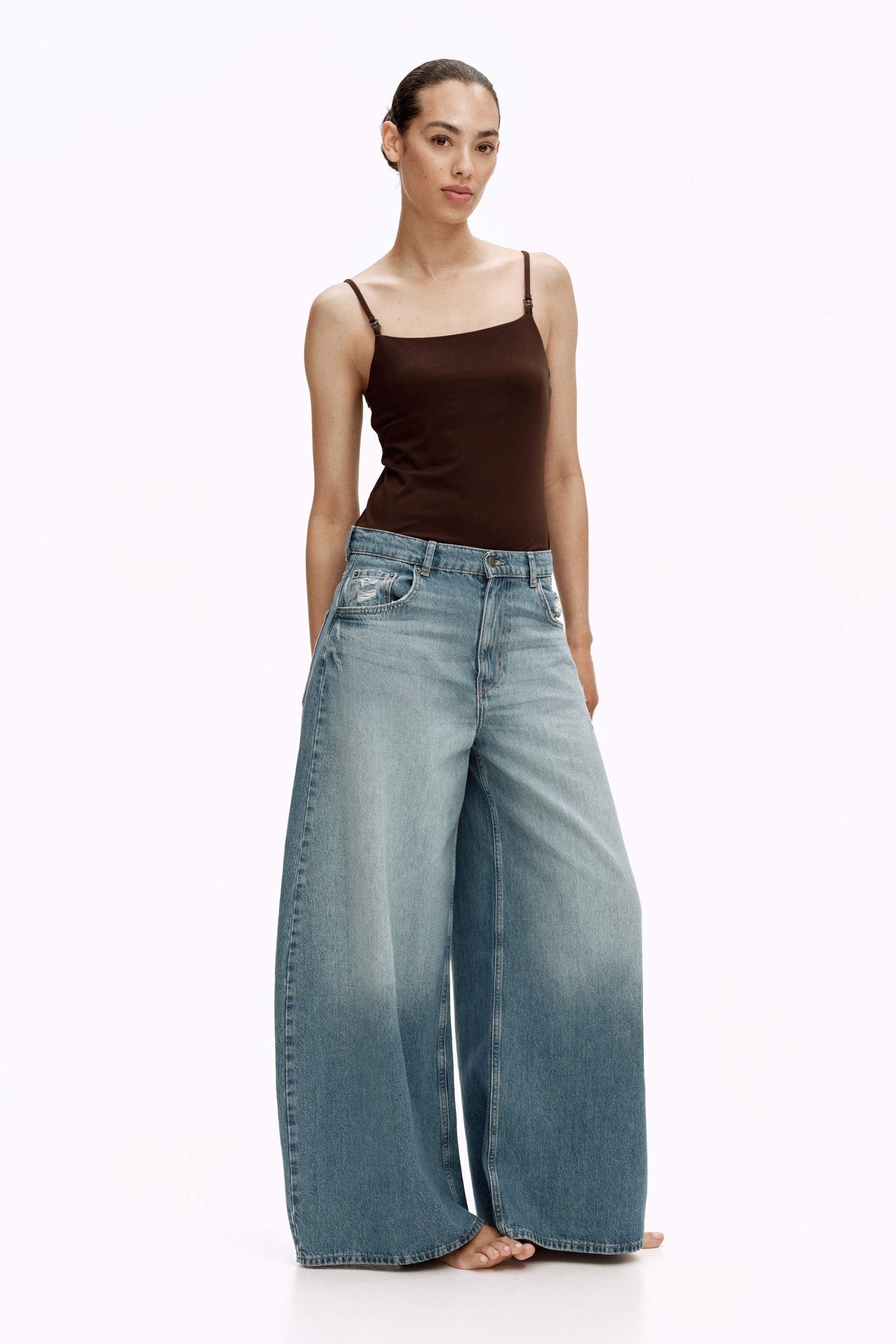 View larger image: These jeans boast a high-waisted, wide-leg design, showcasing a light blue wash that's subtly distressed, with a gradual darkening towards the hem. They feature front pockets and create a full, flowing silhouette.