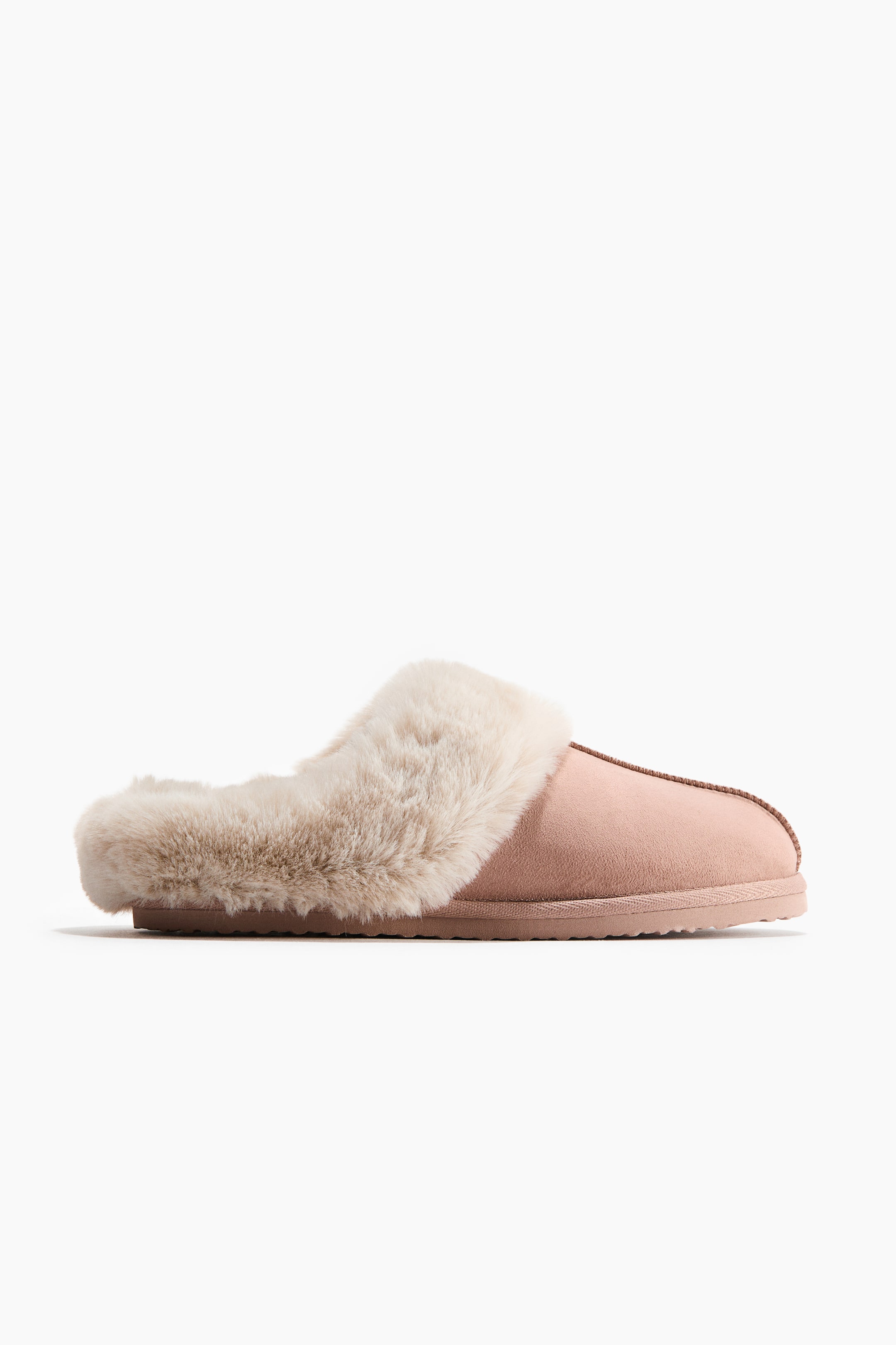 View larger image: A pink slipper is shown in side view, featuring a faux suede upper with cream-colored faux fur trimming the opening. Stitching details the toe and side, and a flat sole is visible underneath.