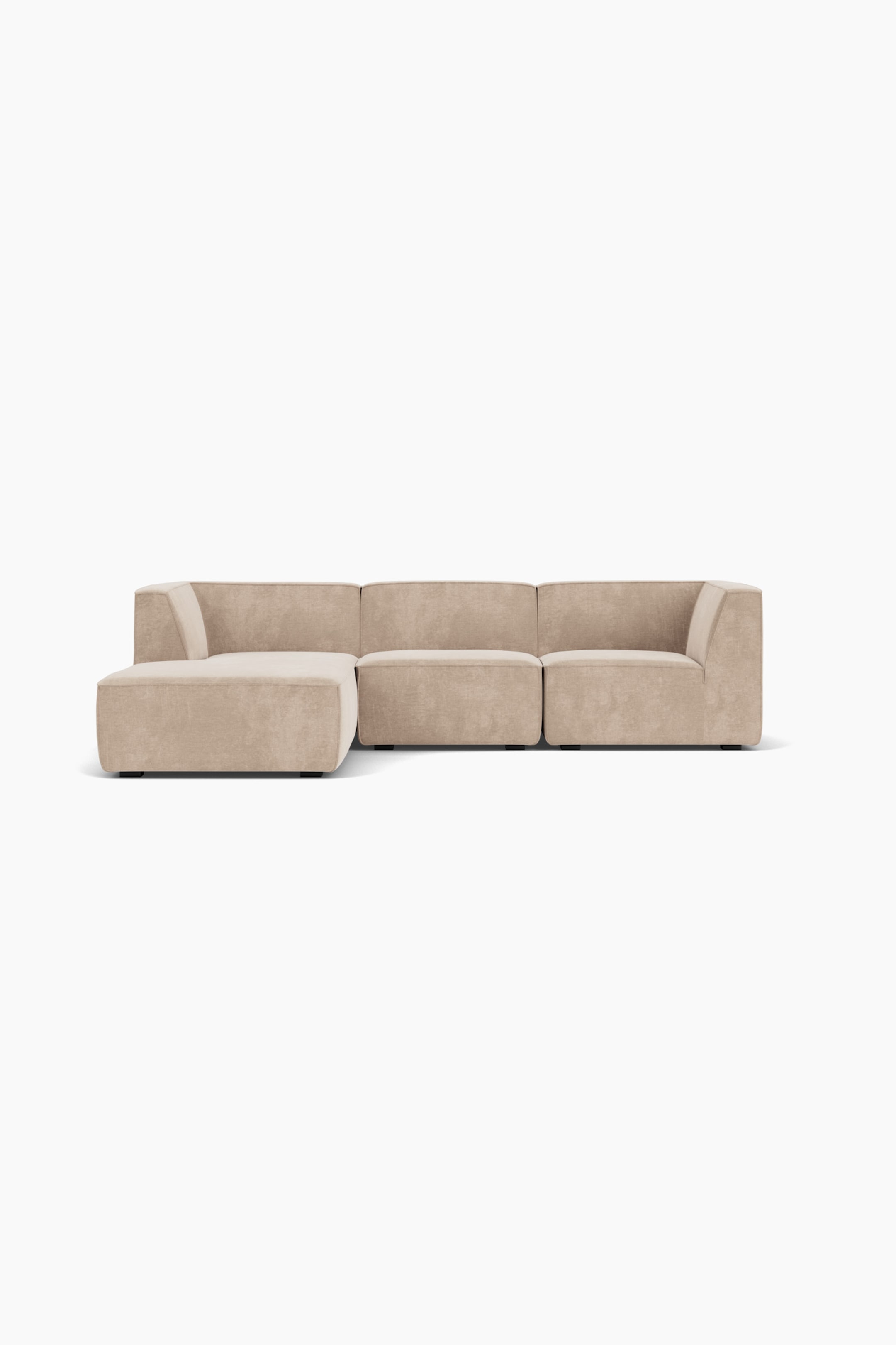 Größeres Bild ansehen: Ein modulares Ecksofa mit hellbeigem Stoffbezug ist frontal ausgerichtet und präsentiert sein flaches, kantiges Design. Das Sofa besteht aus drei verbundenen Einheiten: einer linken Chaiselongue mit integrierter Rückenlehne, einer mittleren Einheit ohne Armlehnen und einer rechten Eckeinheit mit niedriger Armlehne.