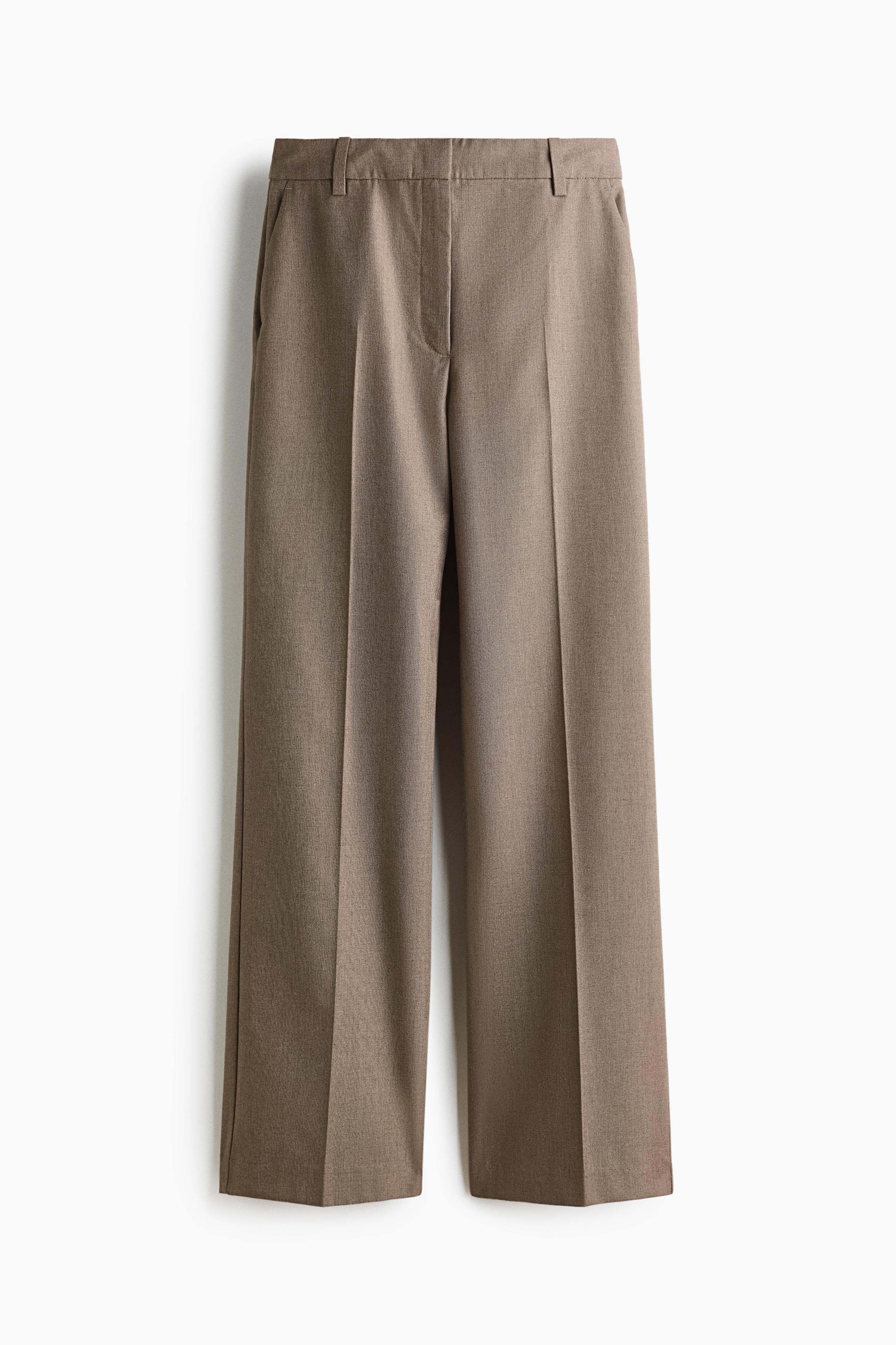 These taupe twill trousers are shown from the front, featuring a straight-leg silhouette with sharp creases running down the centre of each leg. They are styled with a matching double-breasted blazer that covers the high waist, with the hems pooling slightly over black sandals.